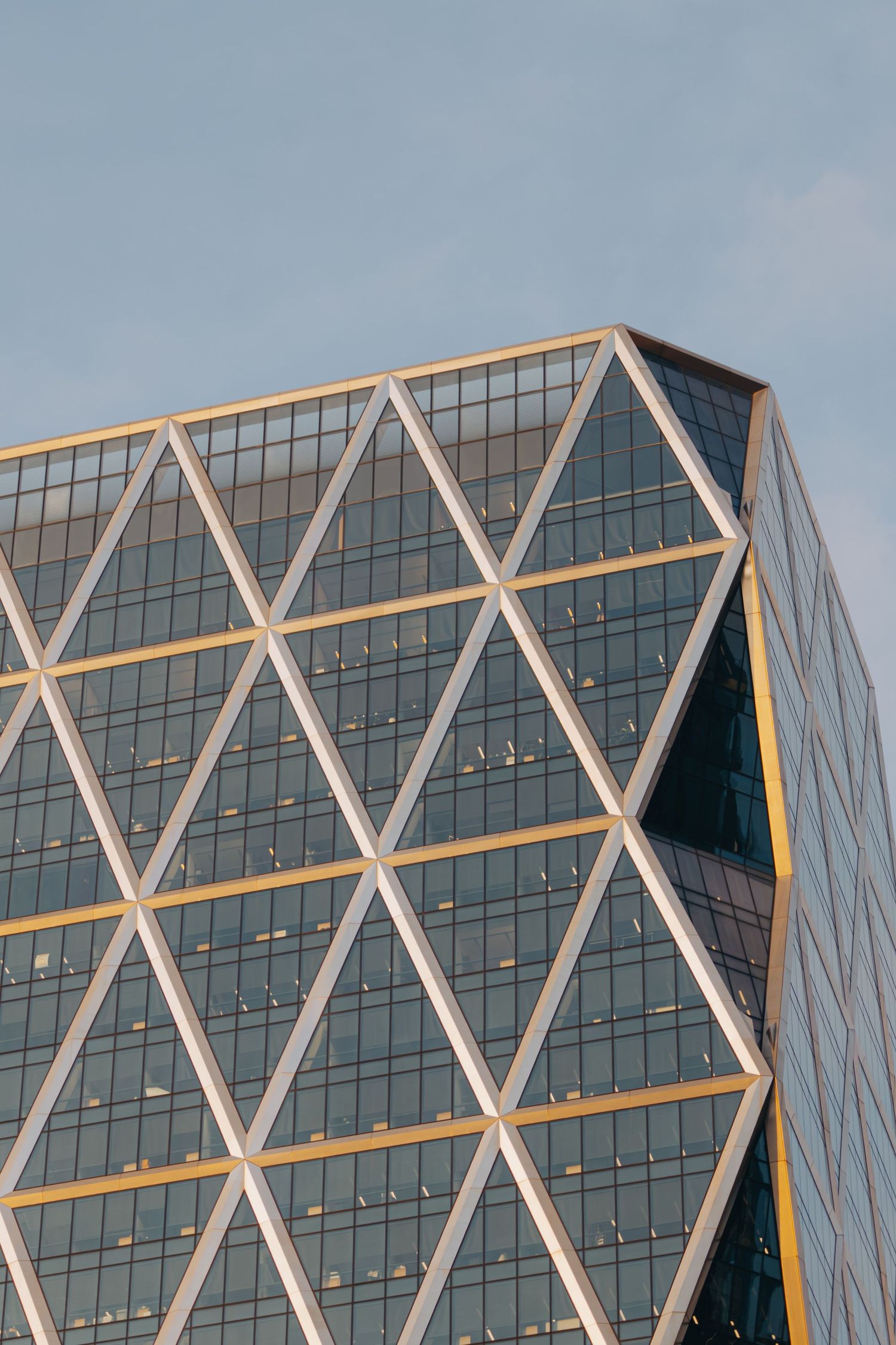 Close-up of a modern glass skyscraper facade featuring a geometric diamond-pattern curtain wall design.