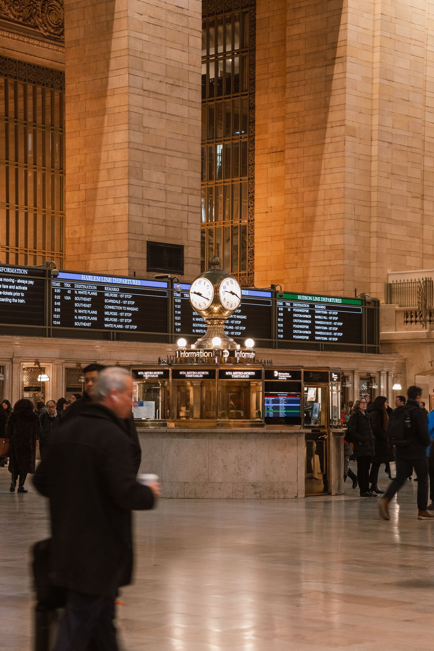 Grand Central Terminal interior showing the famous opal clock atop the information booth with commuters walking by.