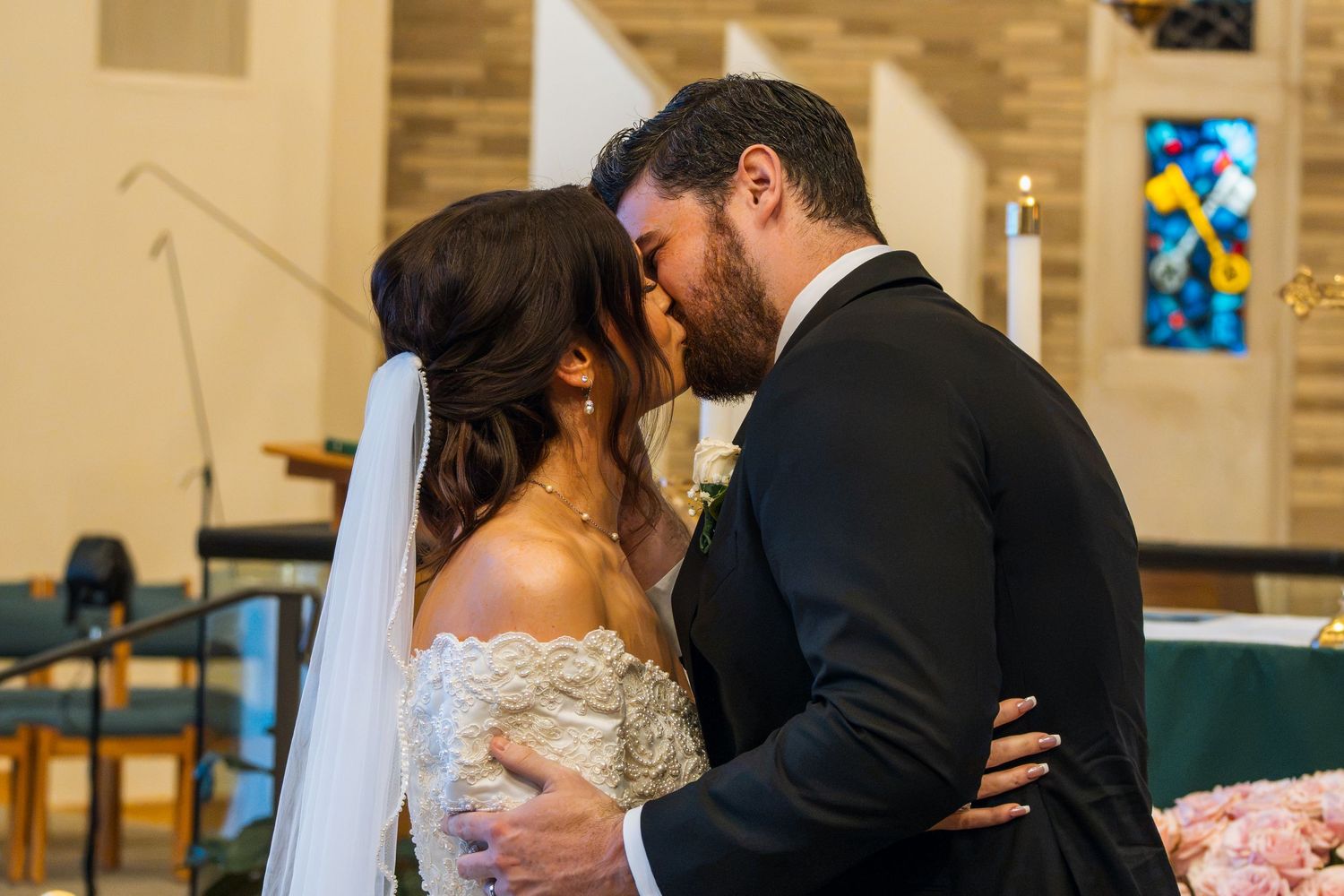 Bride and groom share their first kiss at the altar during a church wedding ceremony.