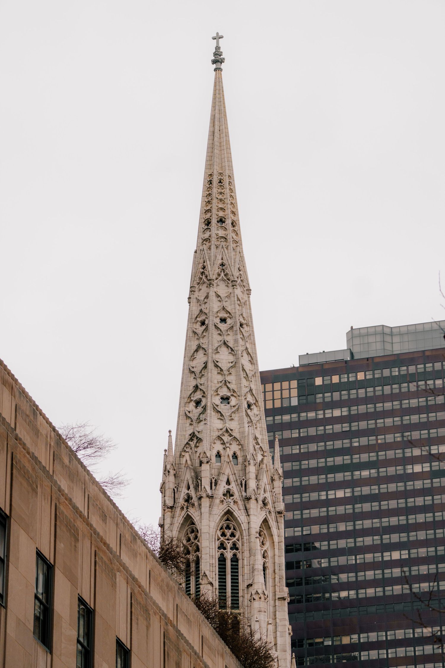 Gothic spire of St. Patrick's Cathedral rising above surrounding buildings in Midtown Manhattan NYC.