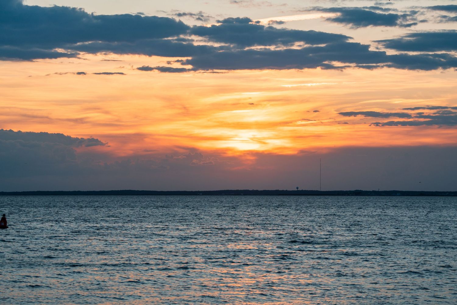 A breathtaking orange sunset over the ocean with dramatic blue clouds and shimmering water reflections.