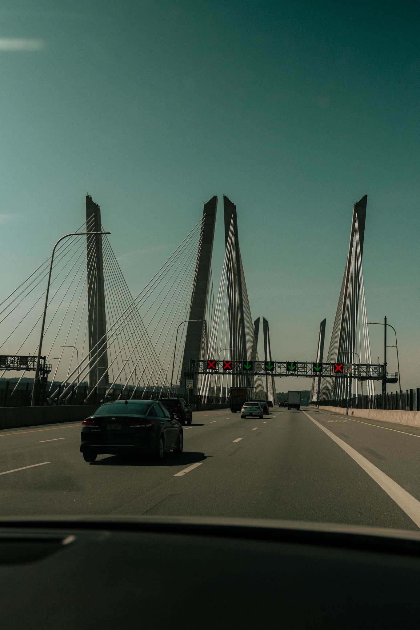 View from inside a car driving across a cable-stayed bridge with toll gantries and light traffic.