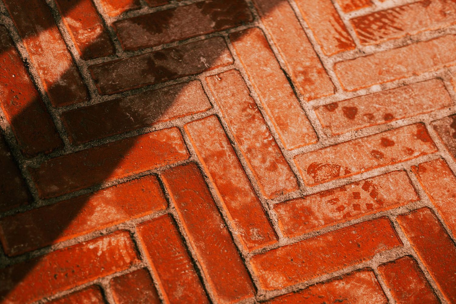 Close-up of red herringbone brick floor pattern with sunlight and shadow in Central Park terrace.