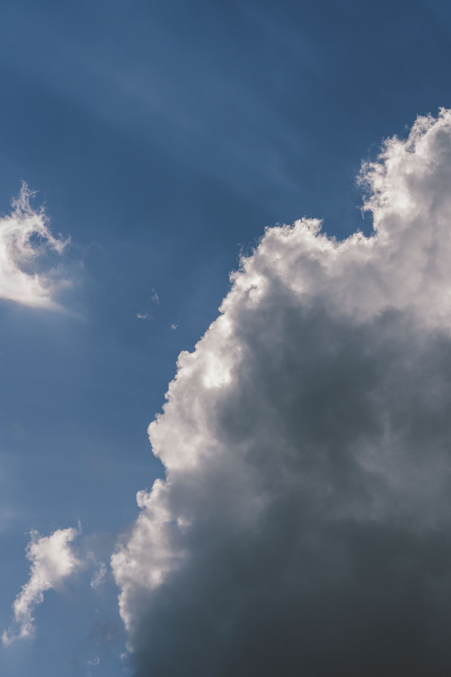 Large white cumulus clouds billowing against a deep blue sky with dramatic lighting.