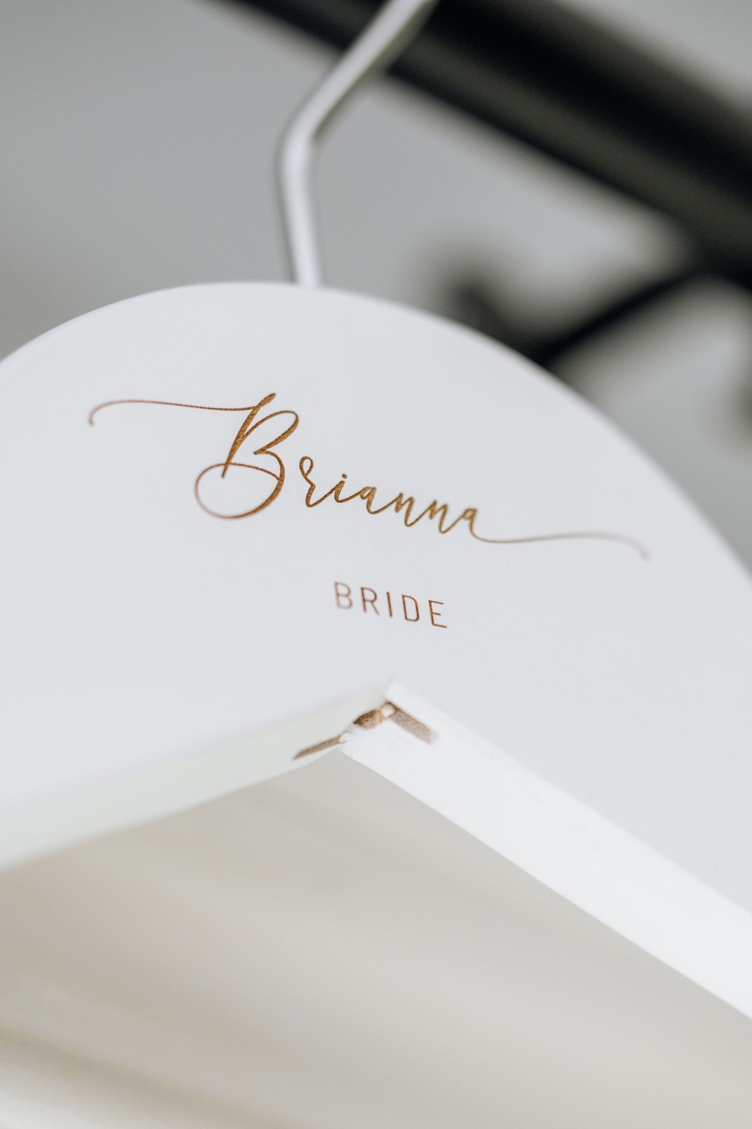 White personalized bride hanger with gold script name Brianna for wedding day bridal party details.