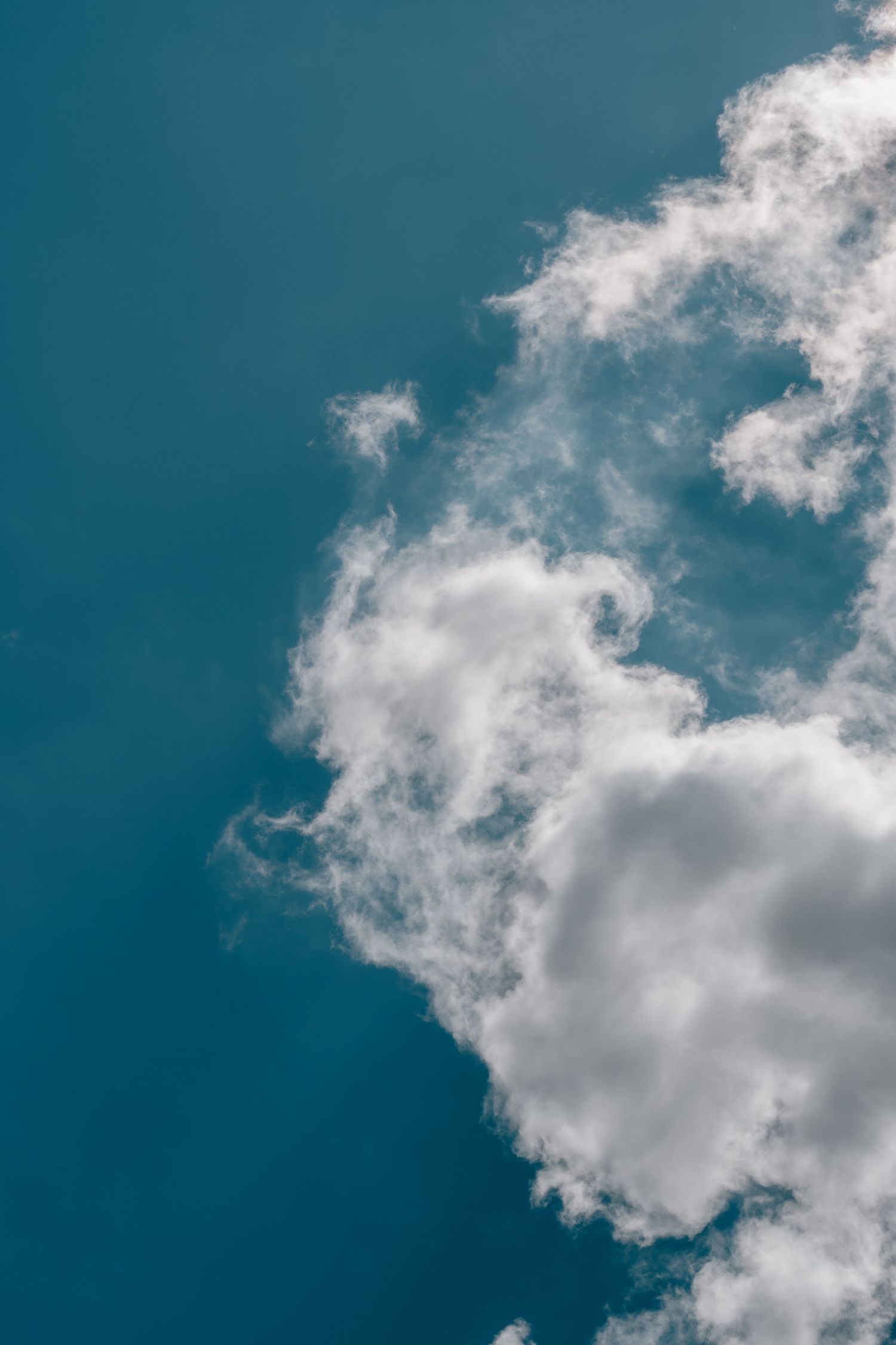 White cumulus clouds drifting across a deep blue sky on a clear day.