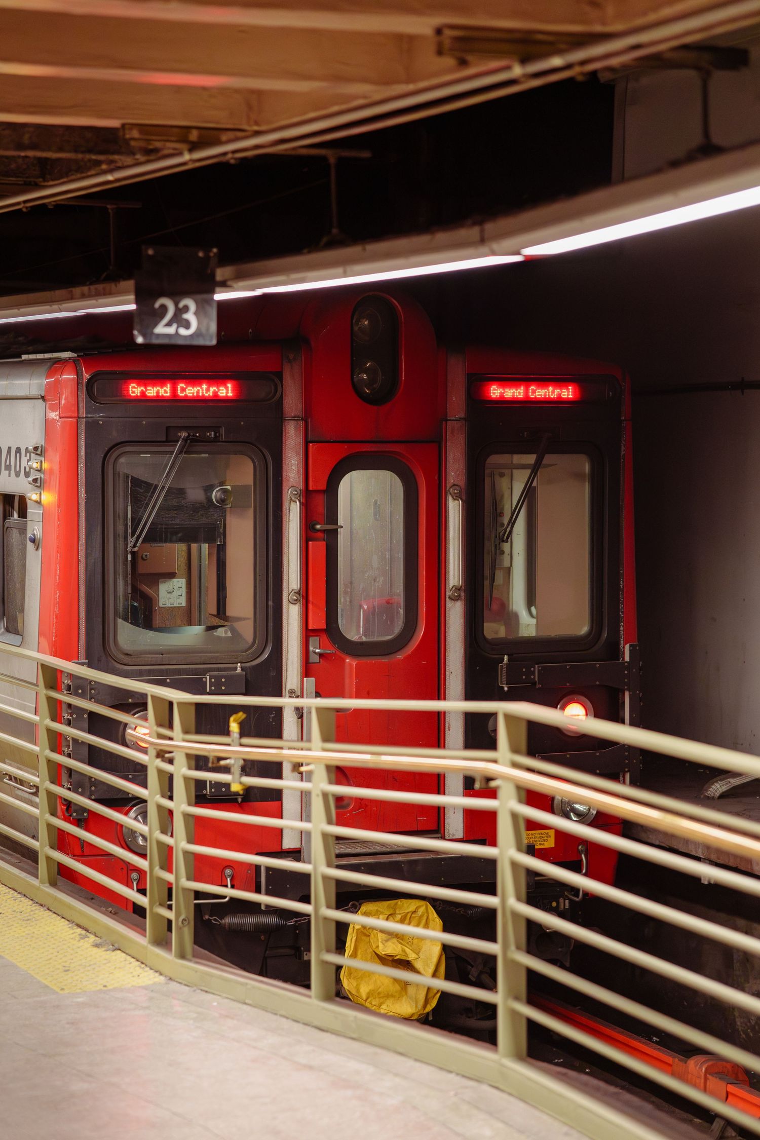 A red Grand Central-bound commuter train sits at platform 23 in a New York rail station.