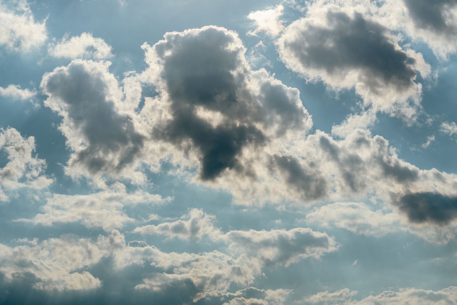Dramatic white and grey cumulus clouds fill a blue sky in natural daylight.