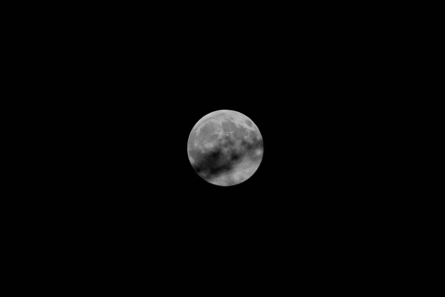 Full moon glowing bright against a dark night sky with visible lunar surface details.