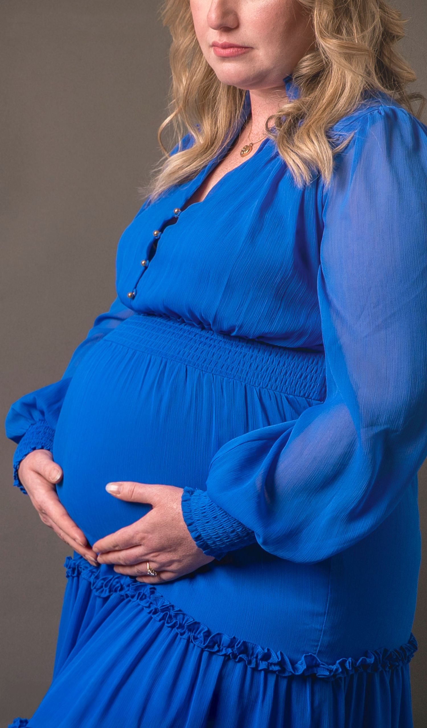 Close-up of parents' hands forming a heart over pregnant belly – maternity photography, in studio North Shore Auckland, Hillcrest