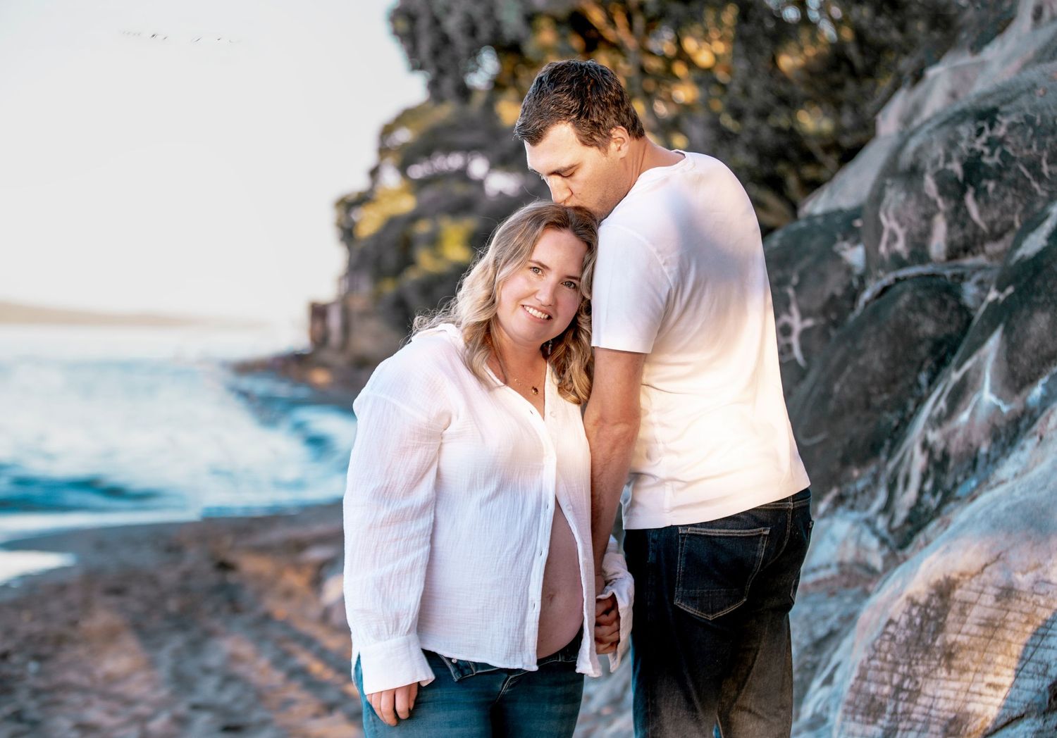Expectant couple embracing by the beach – maternity photographer Auckland North Shore, Mairangi Bay Beach.