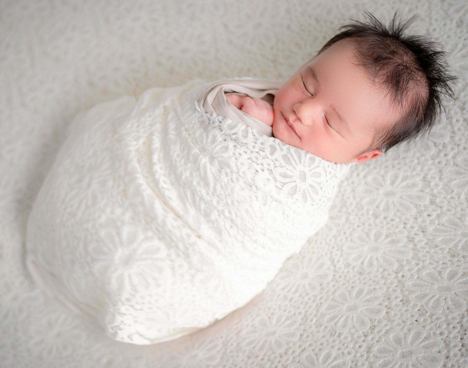 In studio Hillcrest North Shore,  Sleeping newborn baby wrapped in white in studio – newborn photography Hillcrest, Auckland North Shore