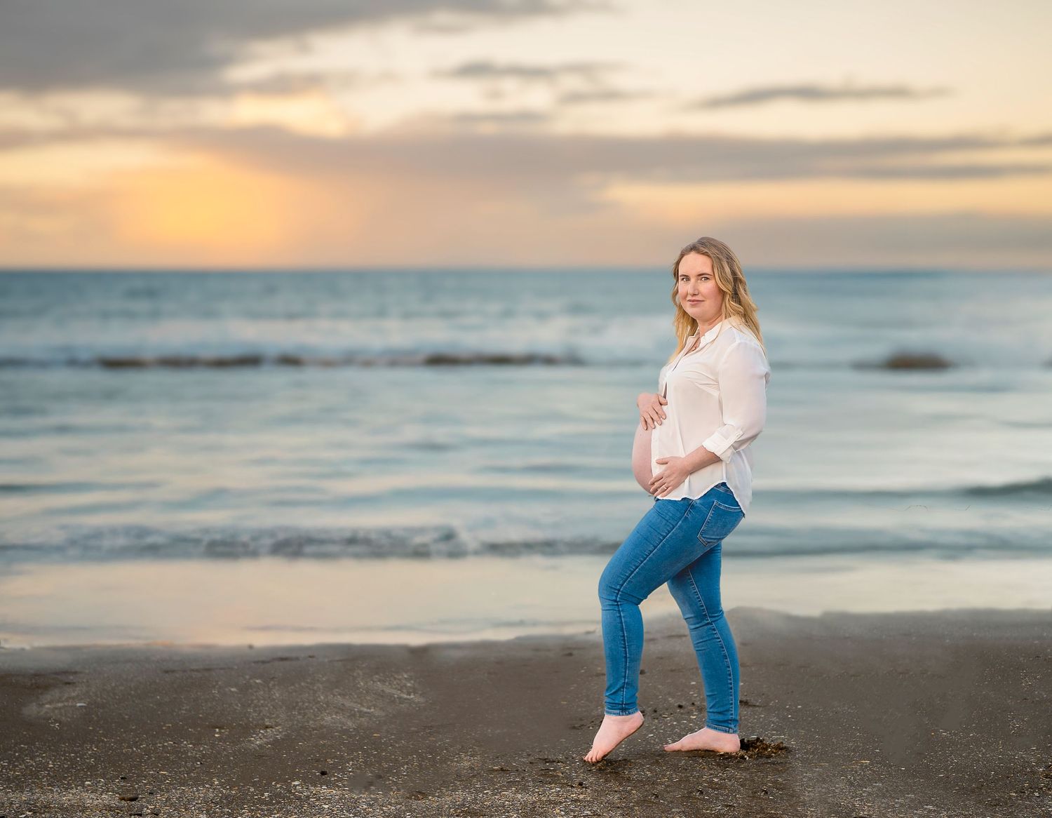 Pregnant woman walking on Long Bay Beach at sunset – maternity photography Auckland North Shore