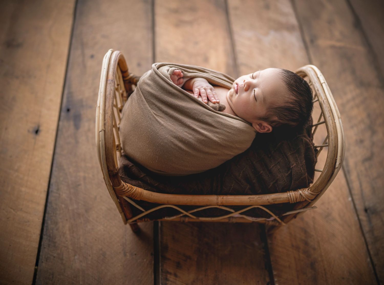 In studio Hillcrest North Shore, Sleeping newborn baby wrapped in neutral tones and posed in a rustic bed – Auckland newborn photography