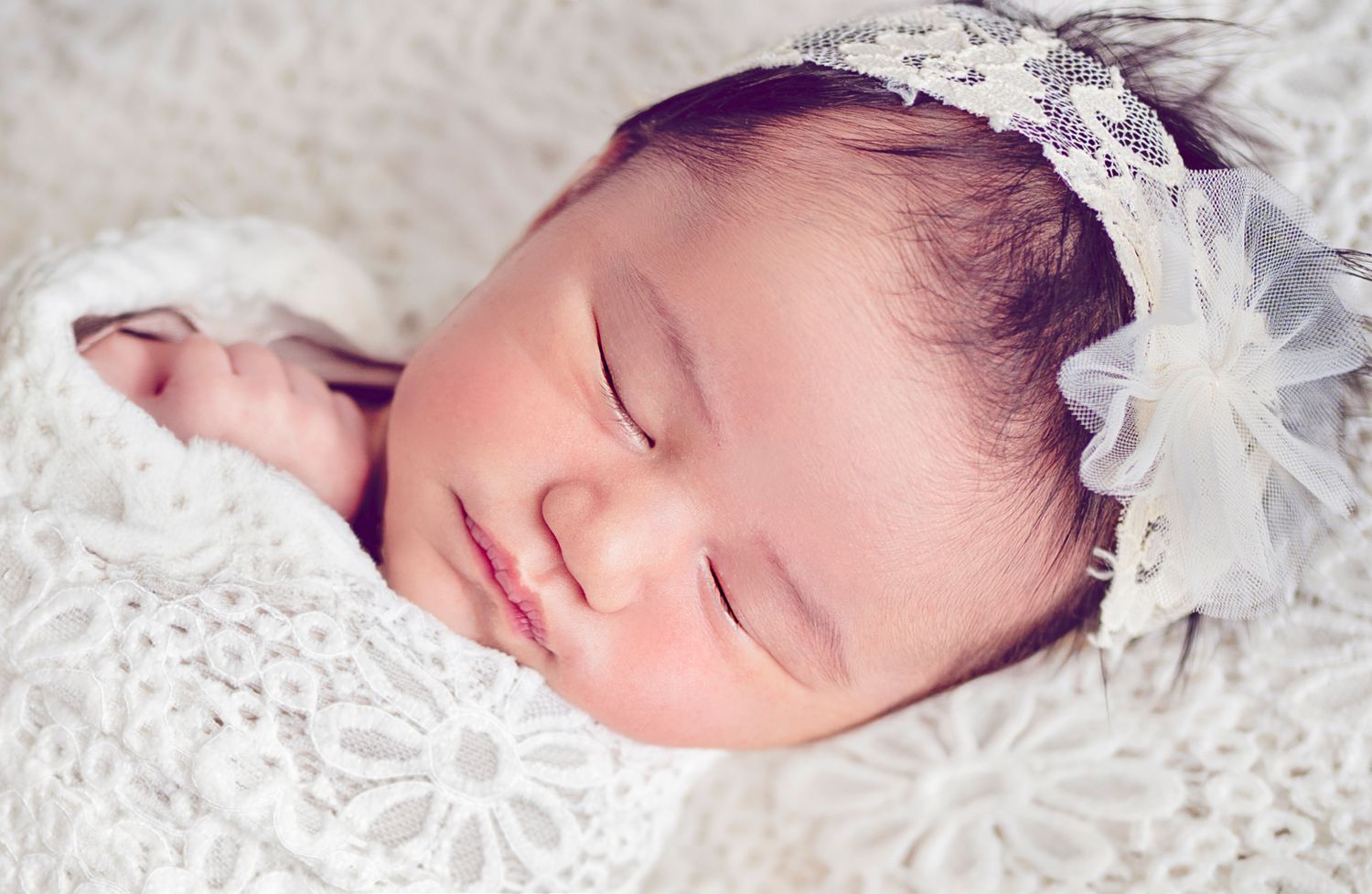 In studio Hillcrest North Shore, Close-up of sleeping newborn baby wearing a delicate floral headband – Auckland North Shore newborn photogr