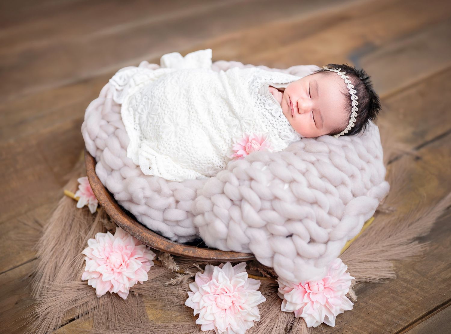 Newborn baby posed in a basket with pink flowers – newborn photography Auckland North Shore