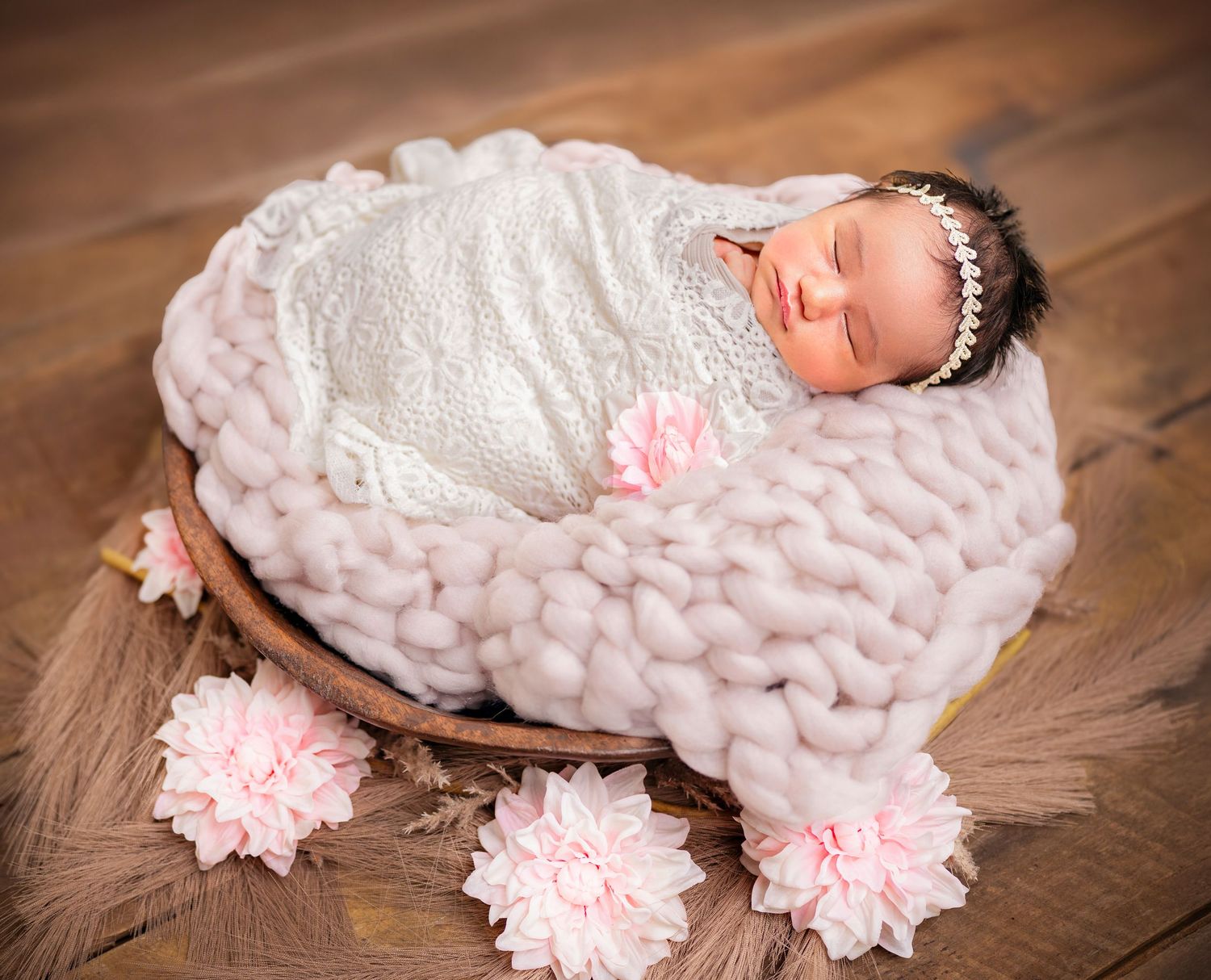 Sleeping newborn baby wrapped in white and posed in a basket with pink flowers – Auckland North Shore newborn photography