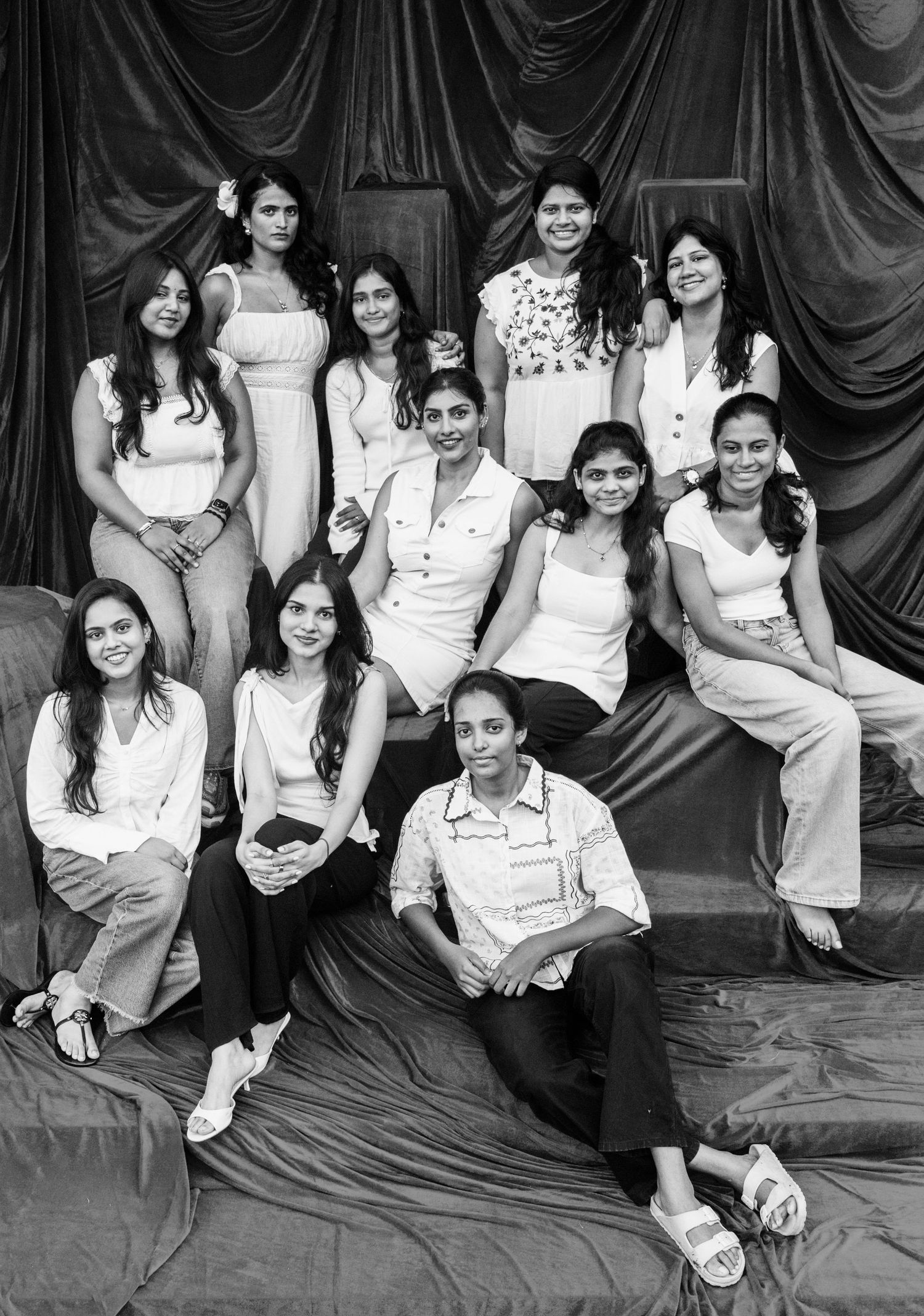Black and white group photo of eleven young women posing together on a draped backdrop.