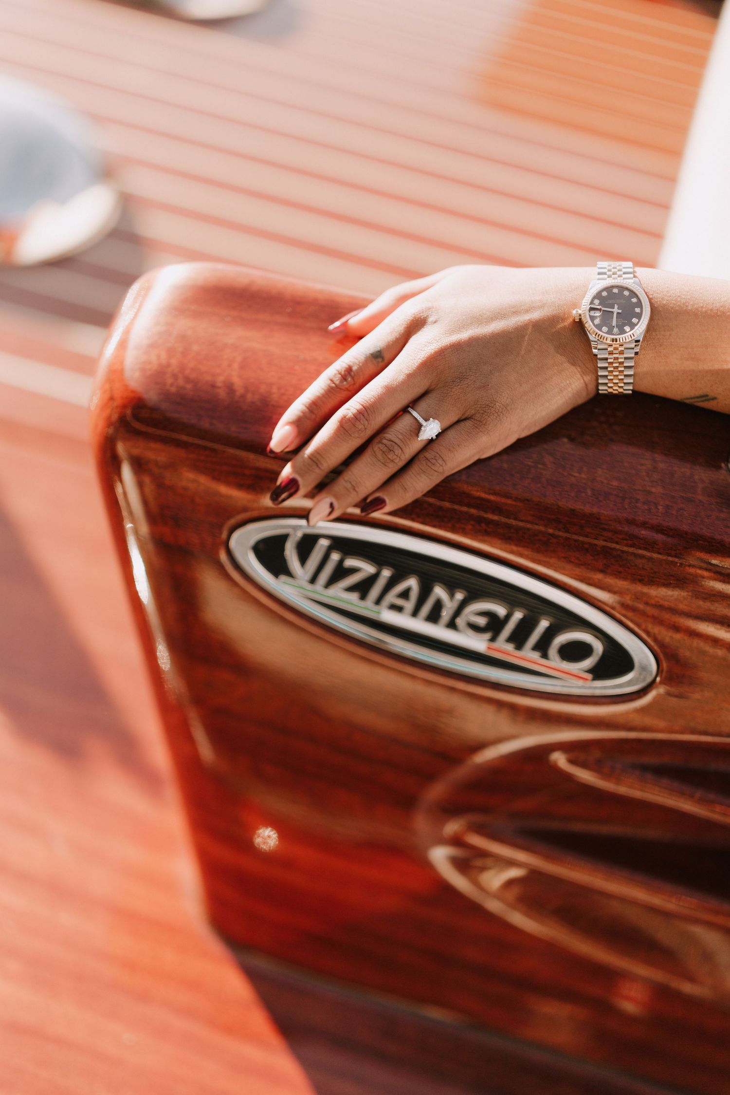Close-up of a woman's hand with engagement ring and watch resting on a Vizianello boat.