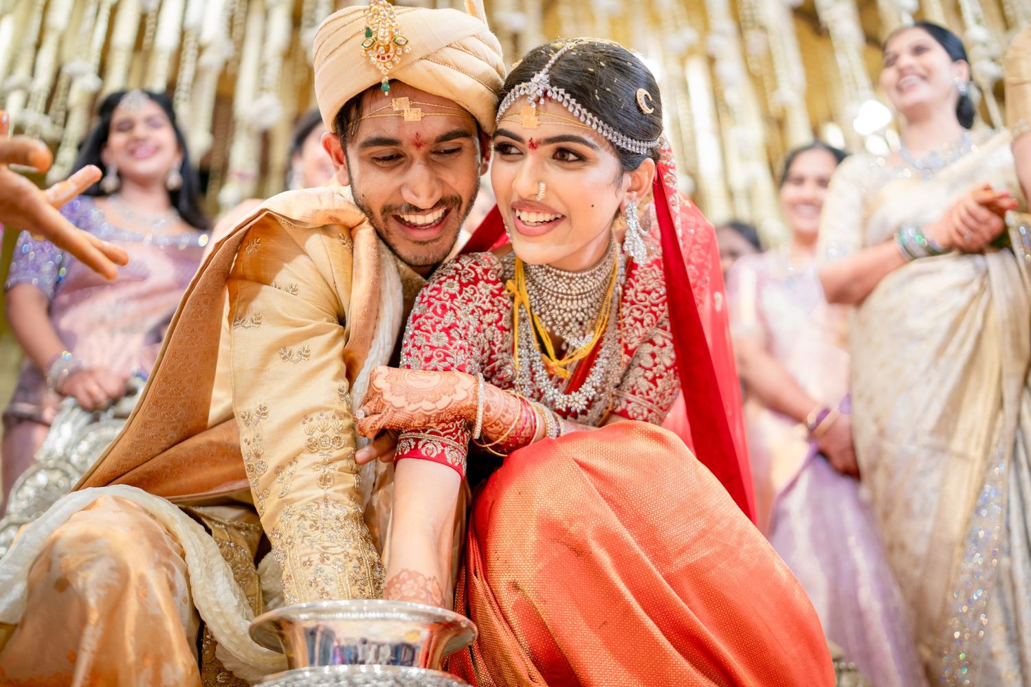 Joyful Indian bride and groom in traditional wedding attire smiling together during colorful Hindu marriage ceremony.
