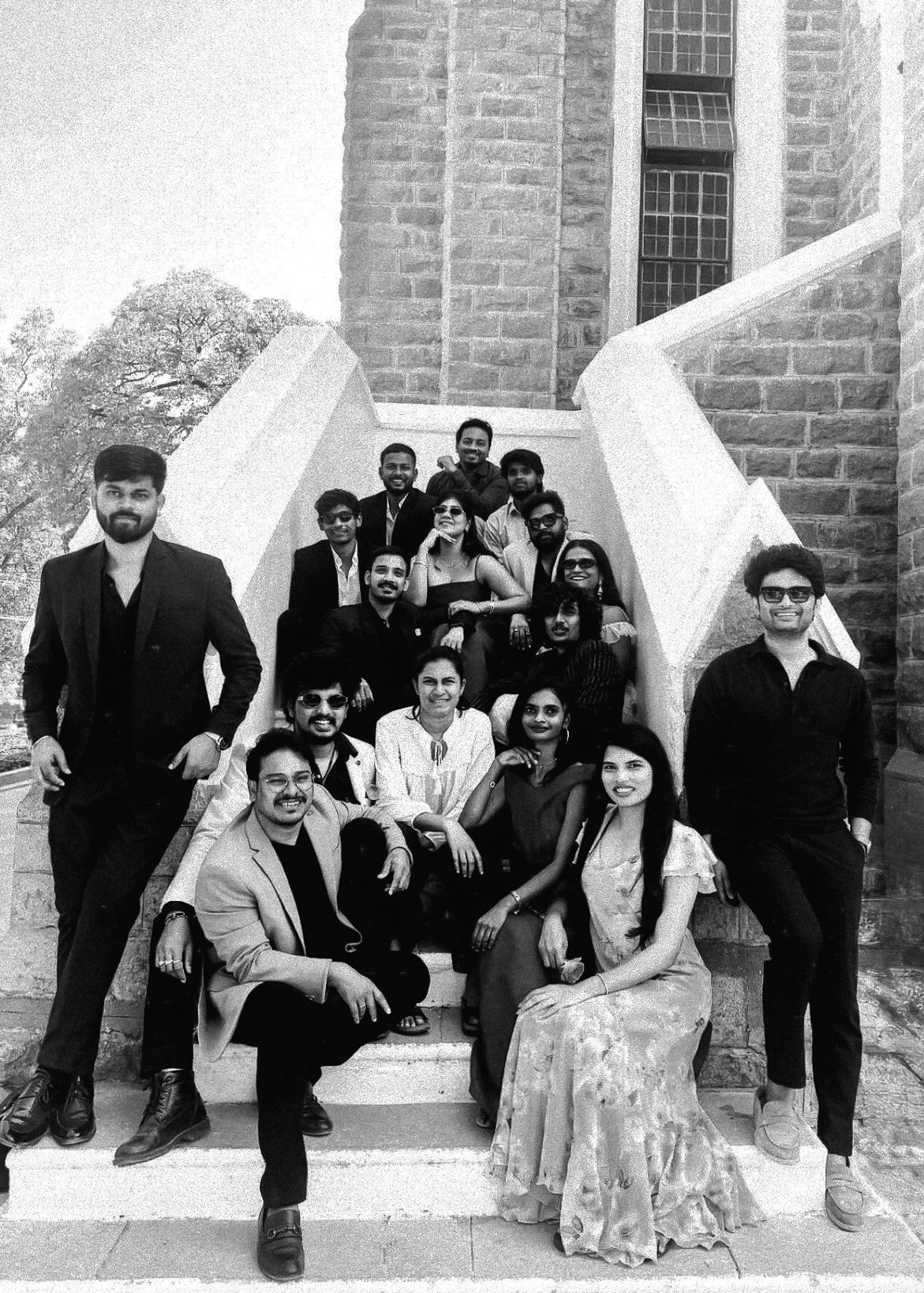 Large group of people posing on stone steps outside a historic building in a black and white photo.