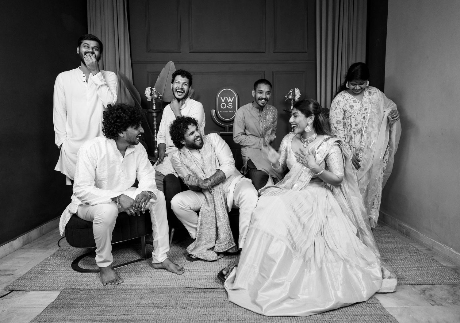 Black and white photo of a joyful group of friends in traditional Indian attire posing together at a celebration.