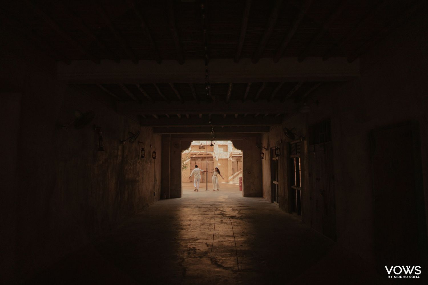 Dark tunnel passageway leading to sunlit ancient adobe ruins, creating dramatic contrast in desert architecture.
