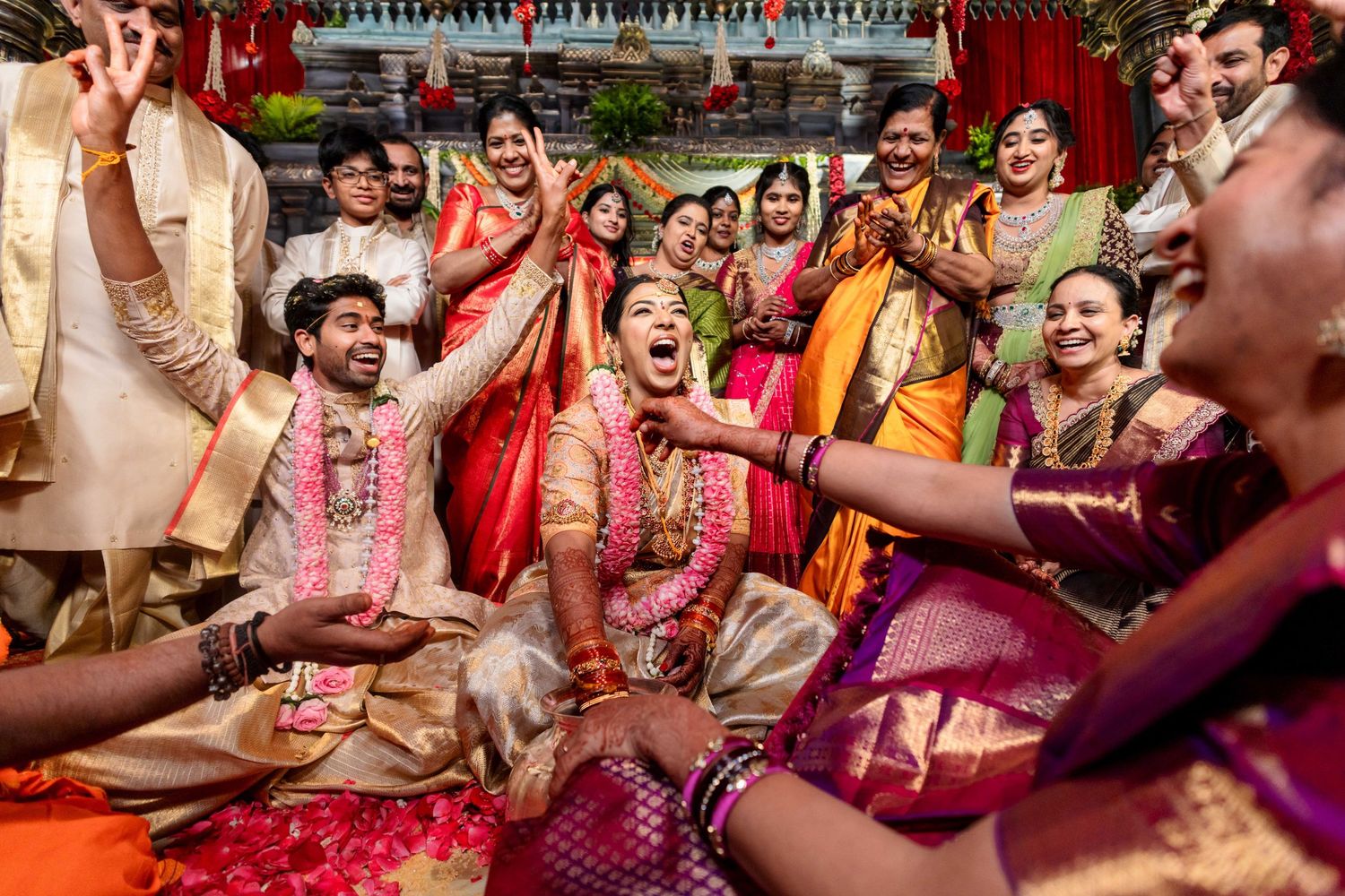 Joyful Indian wedding ceremony with bride and groom surrounded by colorful traditionally dressed family members celebrating.