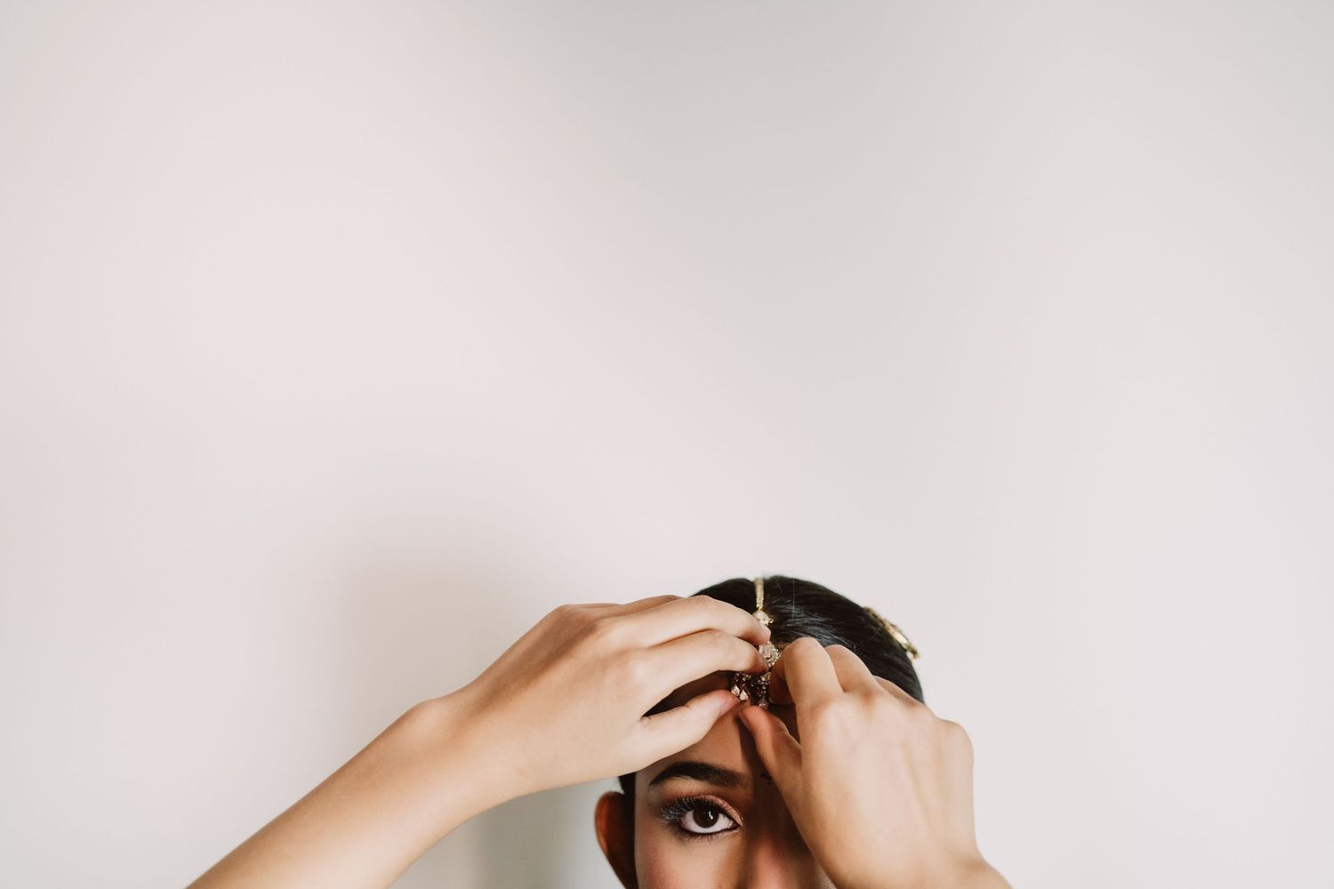 Person holding a hair clip against their forehead, partially covering their face against a white background.