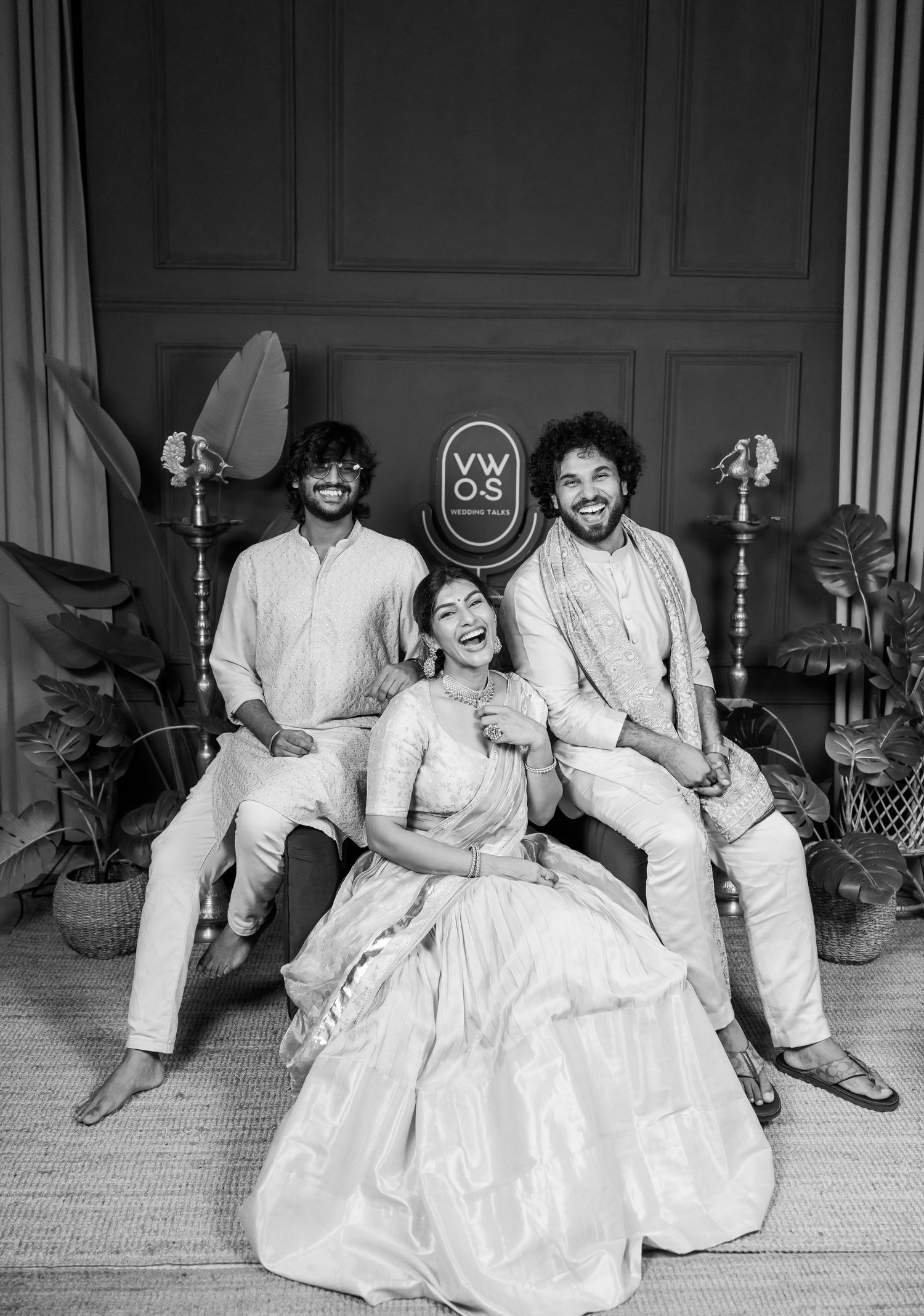 Black and white photo of three people in traditional Indian attire posing together at a festive celebration.