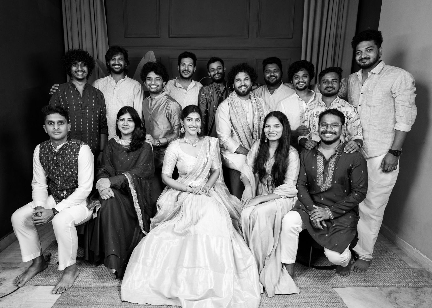 Black and white group photo of Indian family in traditional attire posing together at a formal celebration.