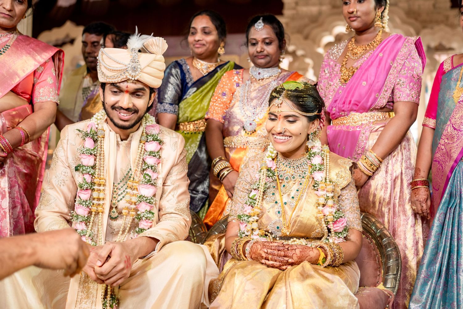 South Indian bride and groom smiling during traditional wedding ceremony with guests.
