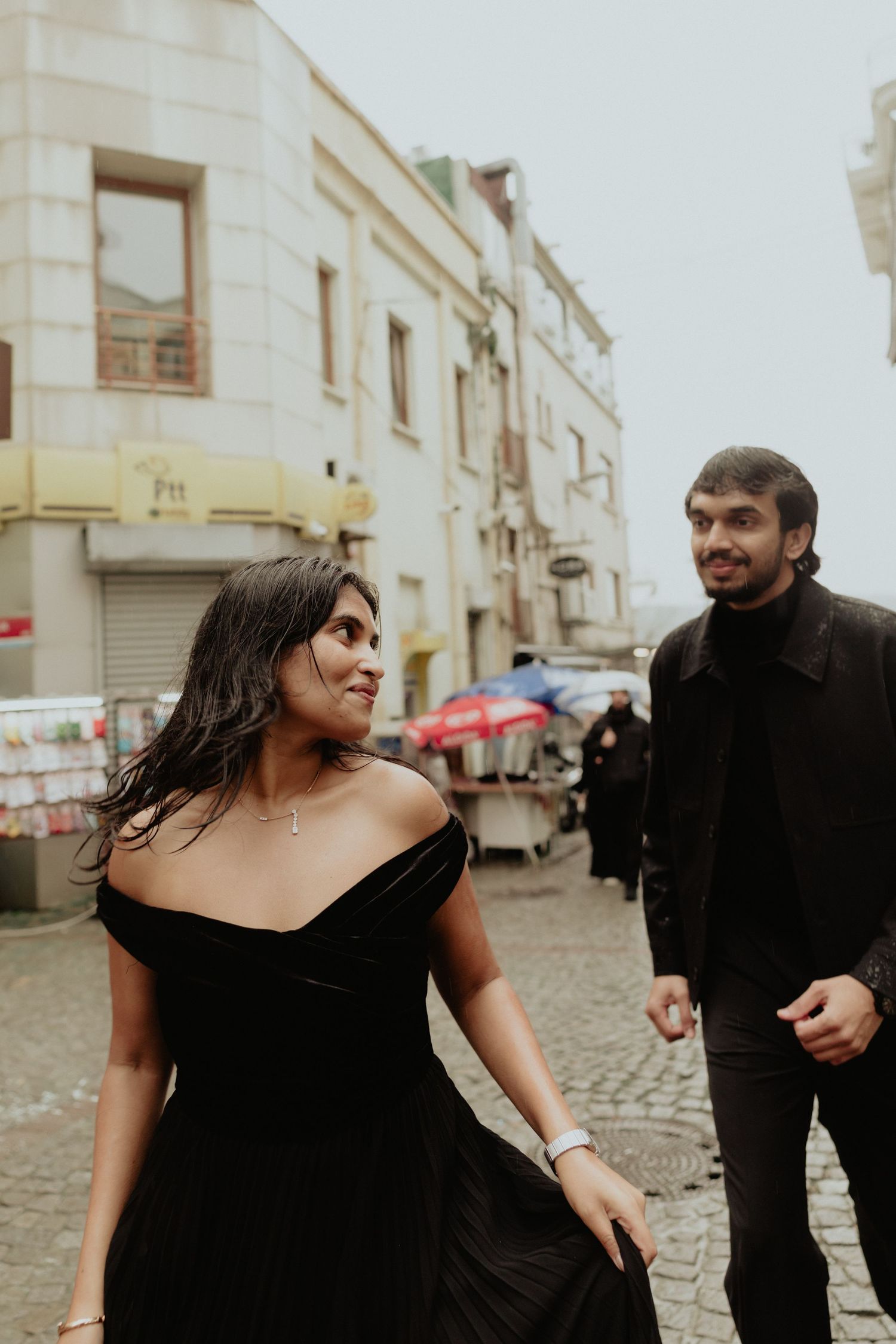 Couple in black outfits walking through cobblestone streets of Istanbul, Turkey.