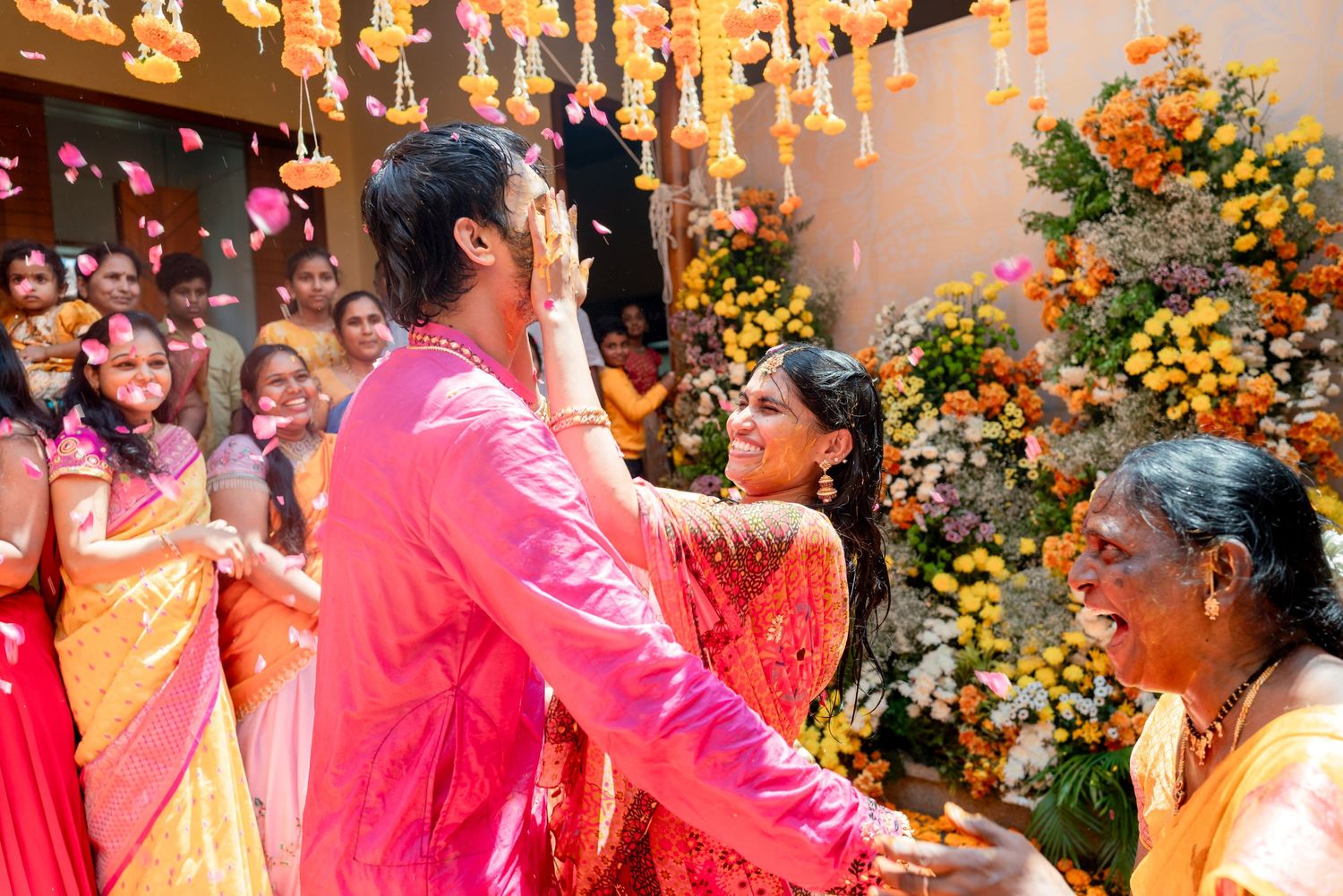 Indian wedding couple in pink and red attire during jaimala ceremony with flower decorations.