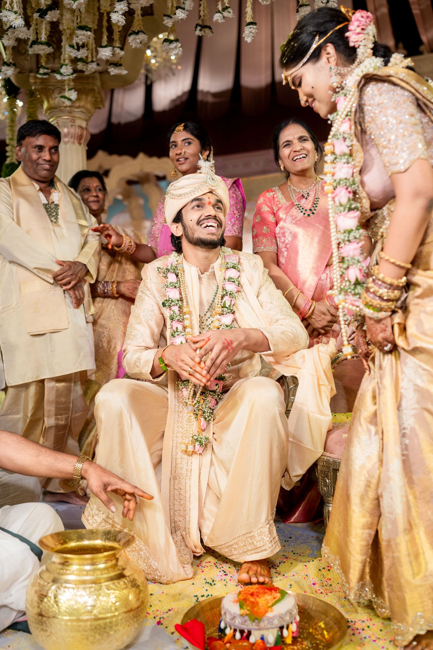 Groom laughing joyfully during traditional South Indian Hindu wedding ceremony with garlands.