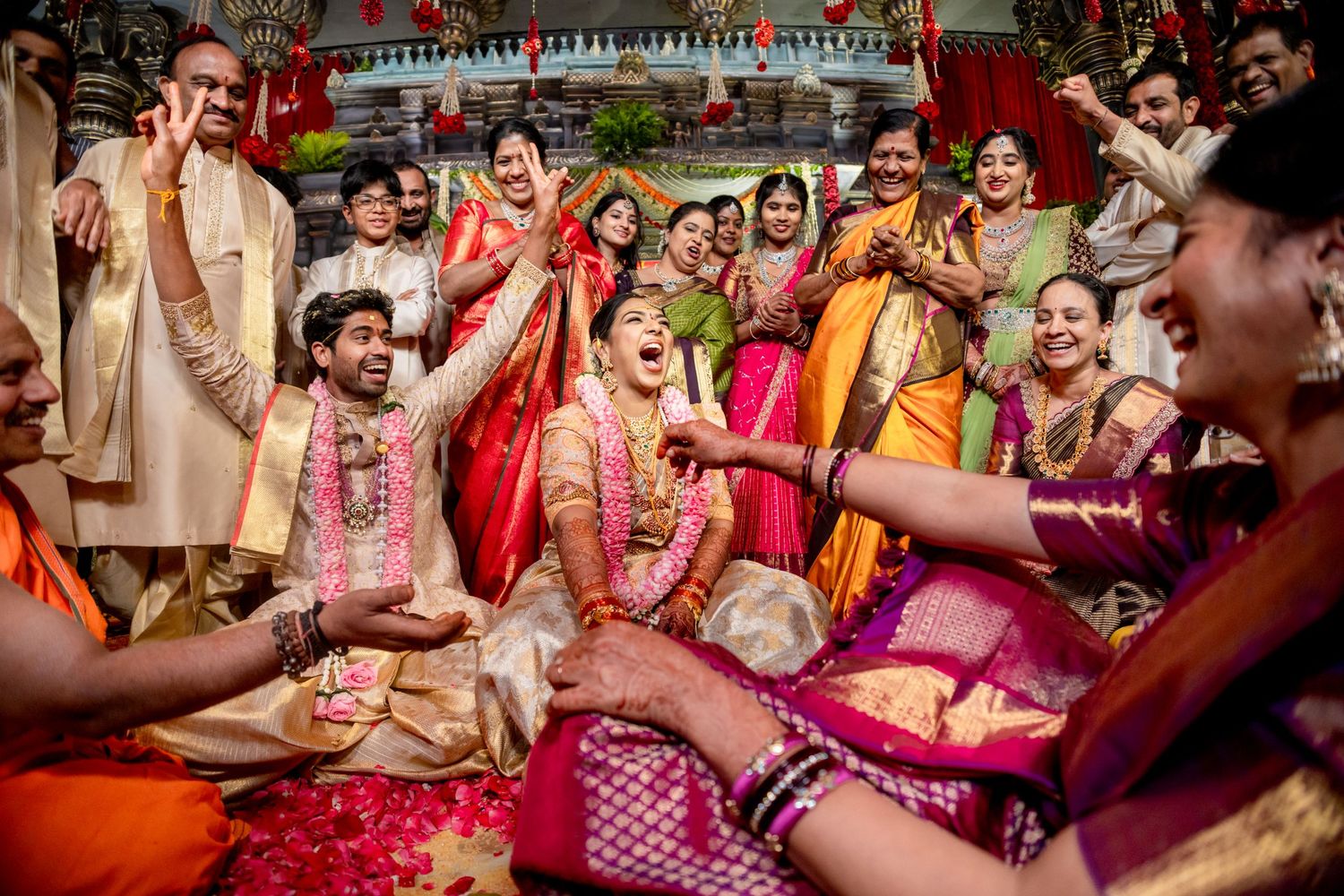 Joyful Indian wedding ceremony with guests in vibrant sarees and traditional attire celebrating together.