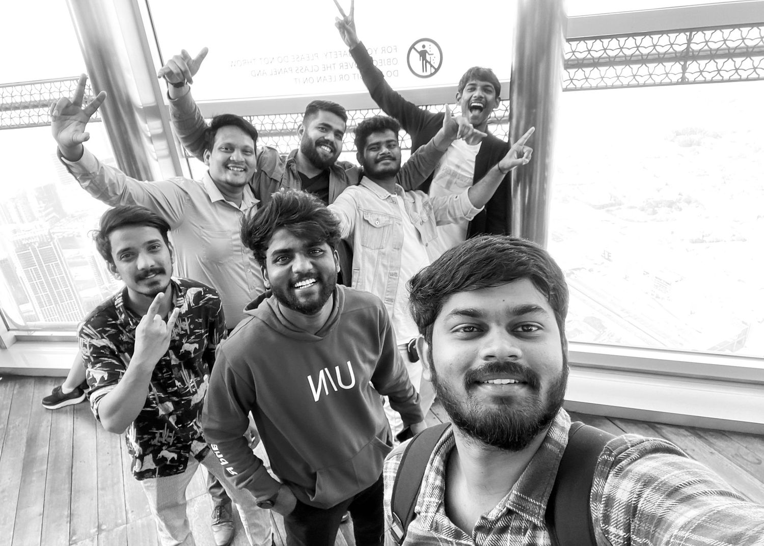 Group of young men posing for a fun selfie on an observation deck in black and white photo.