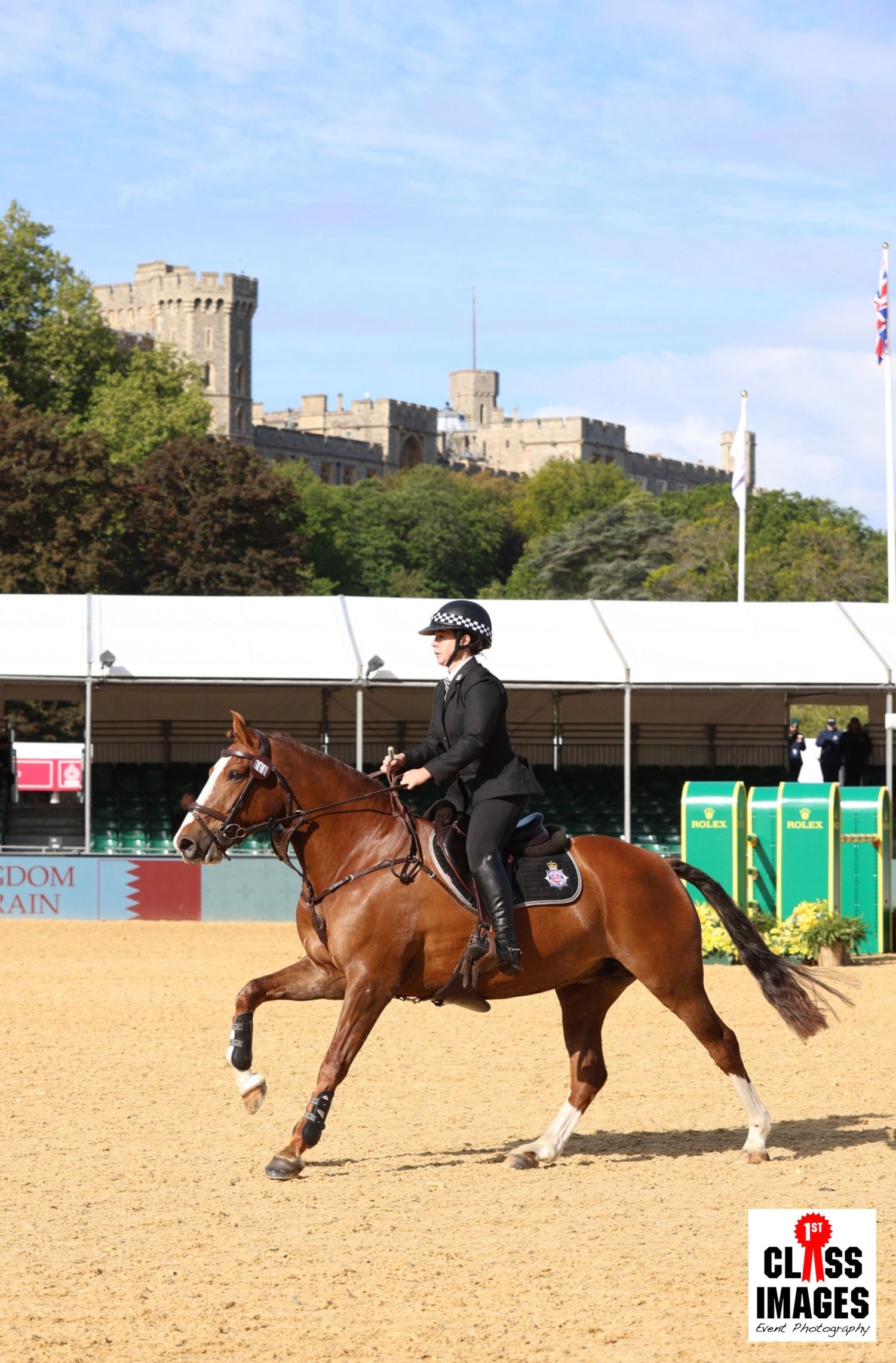Police officer riding a chestnut horse at Windsor Castle equestrian event on a sunny day.