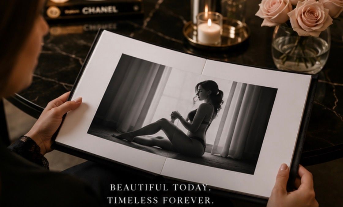 Woman holding open a boudoir photo book with black and white image, beside roses and candle.