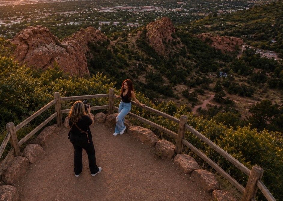 Two women at a scenic overlook at Garden of the Gods, Colorado, with red rock formations and valley views at sunset.