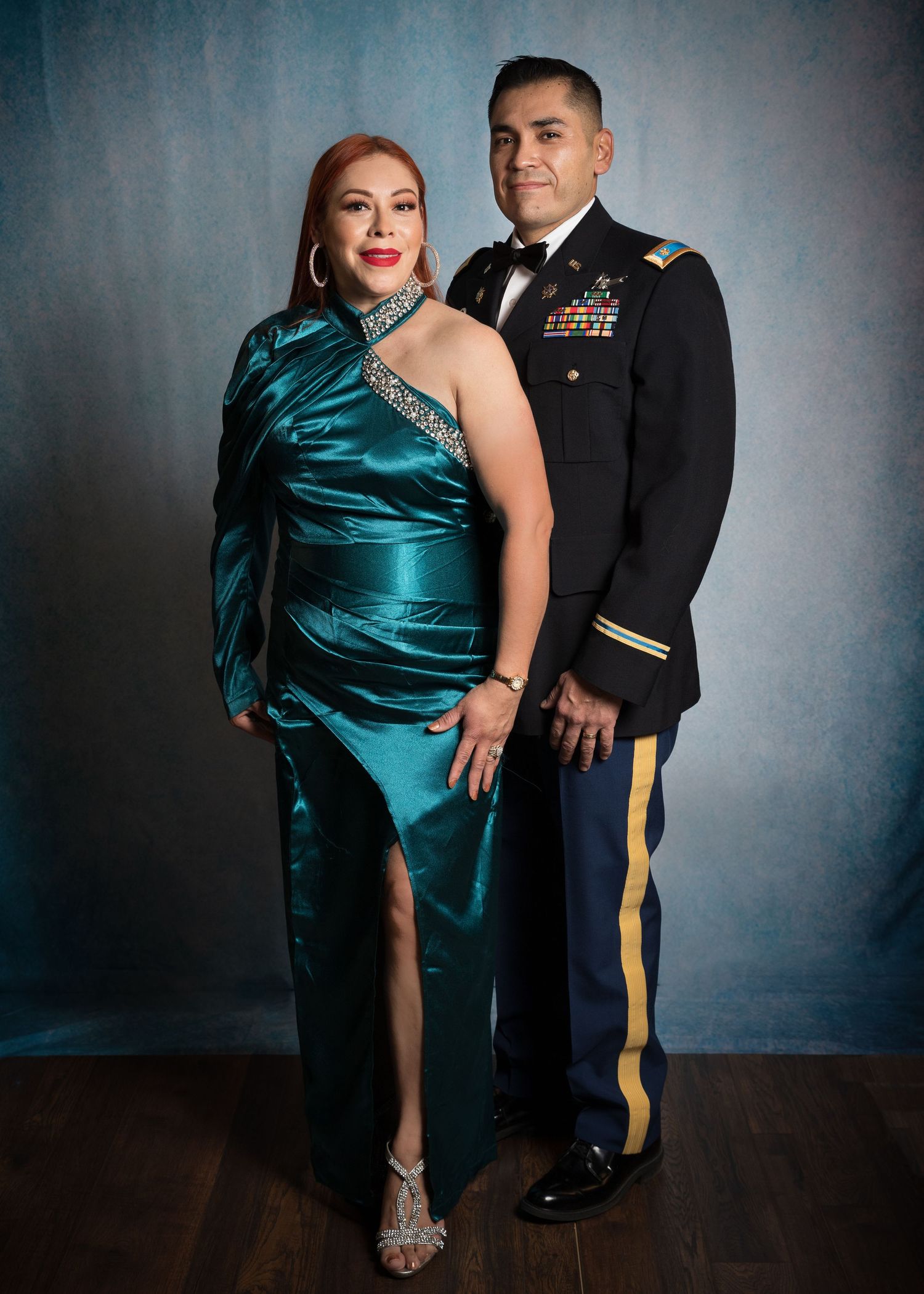 Couple at military formal event, woman in teal satin gown and man in Army dress uniform with bow tie.