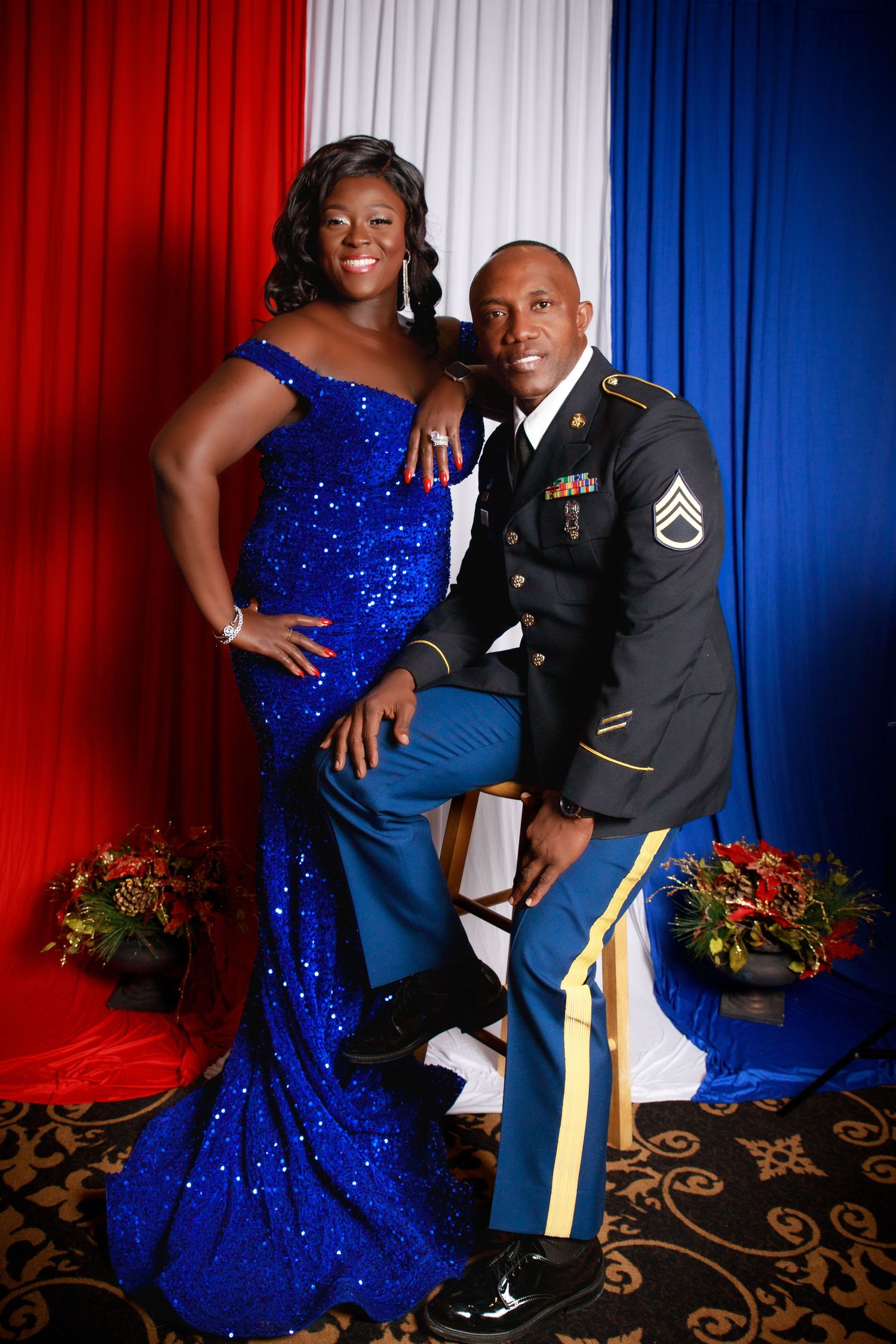 Couple at military ball, woman in royal blue sequin gown and man in Army dress uniform with medals.