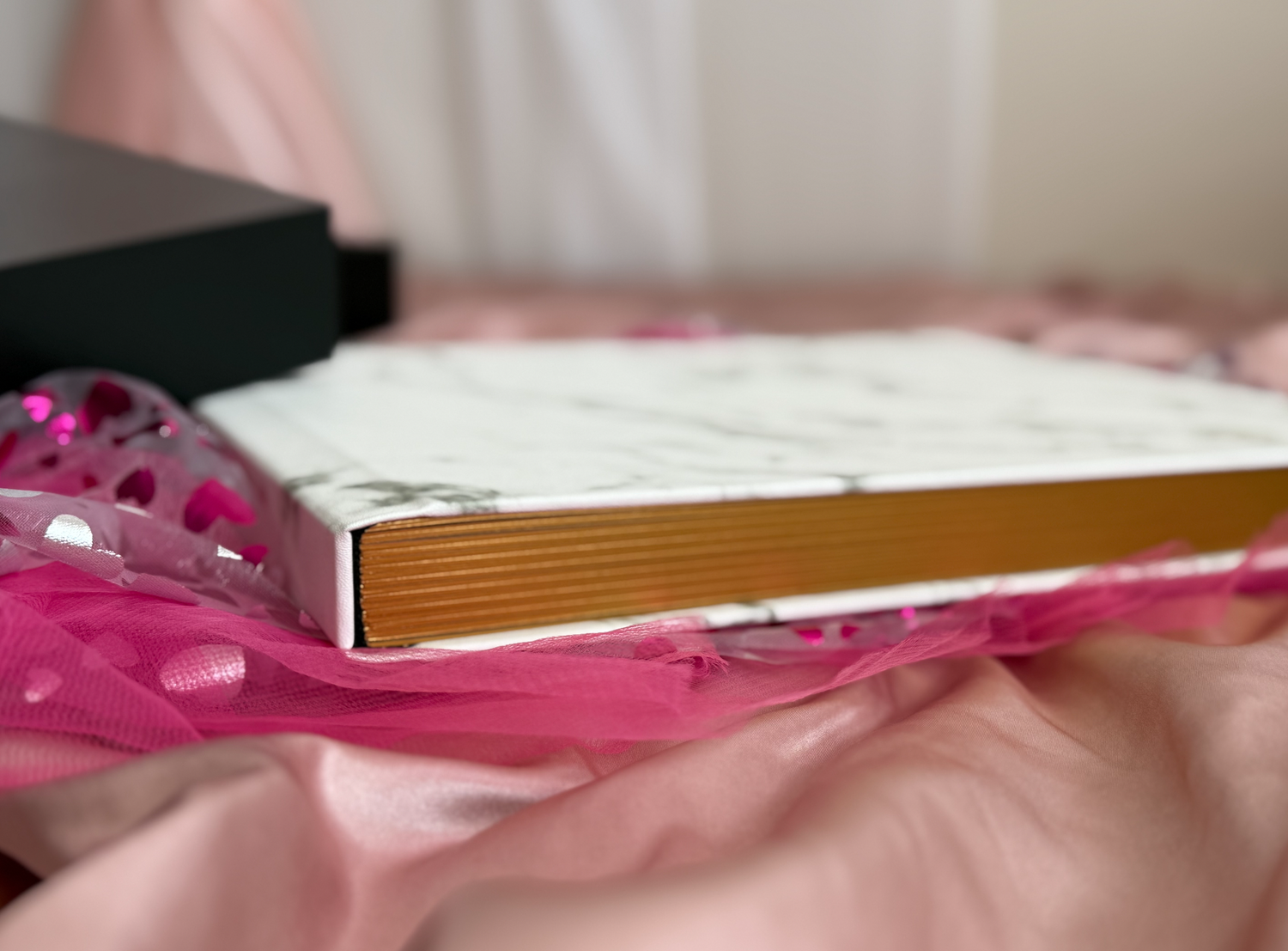 Marble hardcover boudoir photo album with gold embossing displayed on decorative crystal table at Nicole Fey Photography boudoir studio.