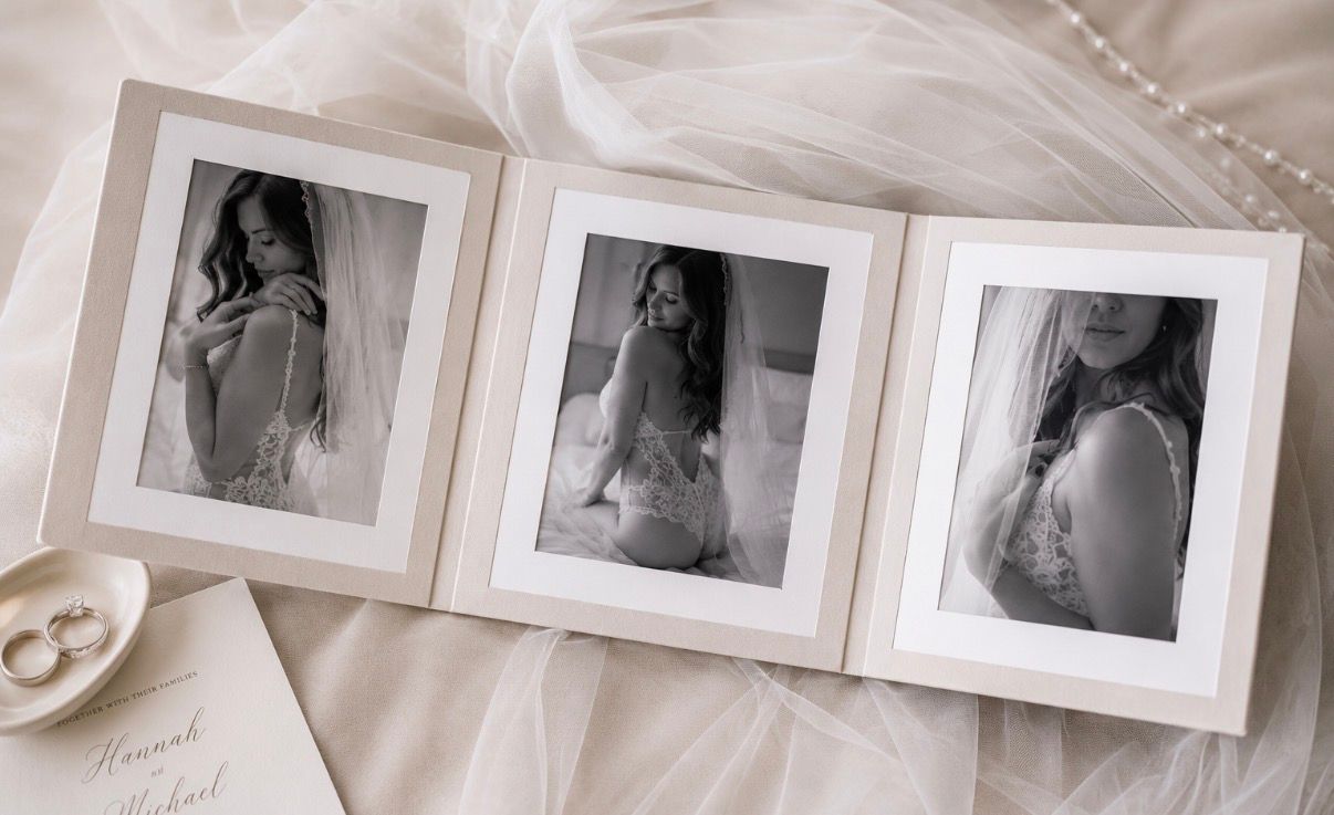 Elegant wedding boudoir photo album open to three black and white portraits of a bride in lingerie on a bed.