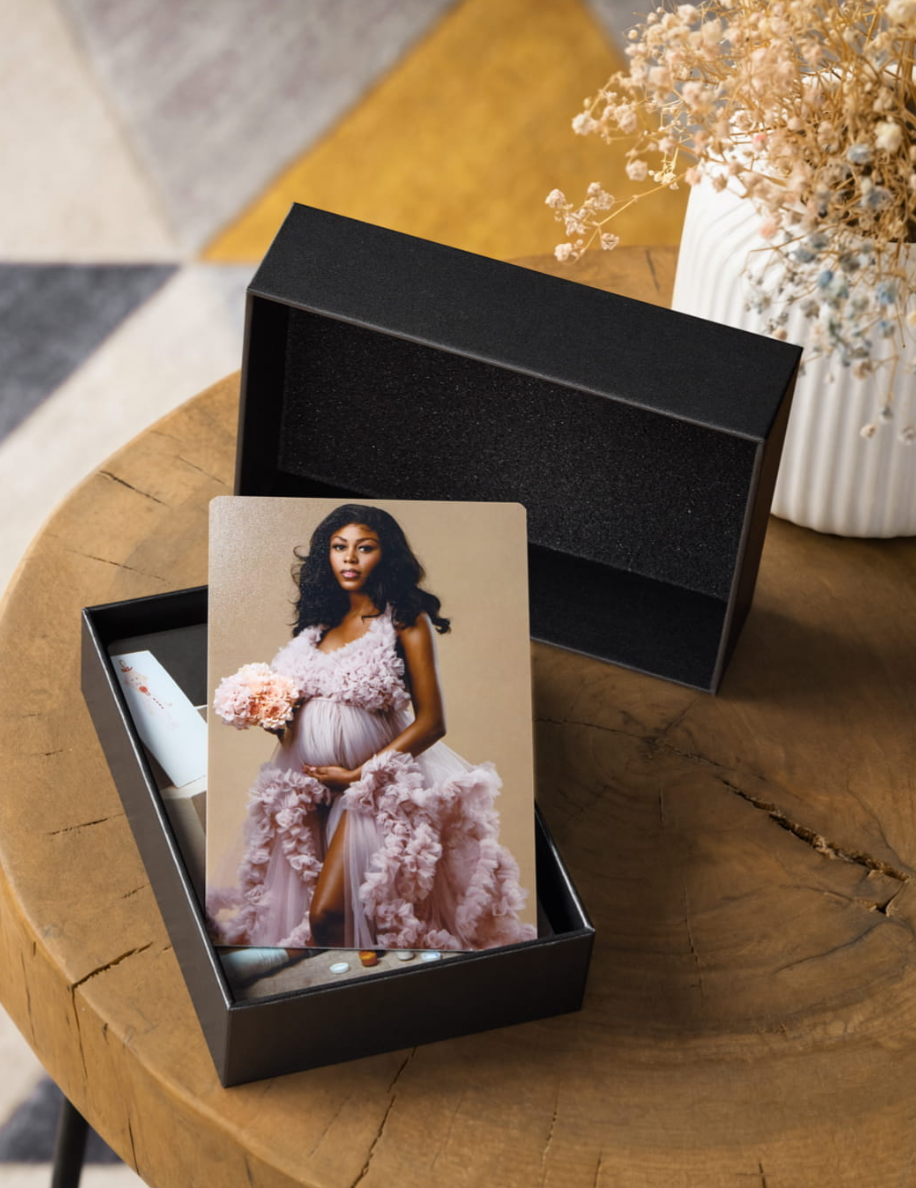 Maternity photo print displayed in black gift box on wooden table.