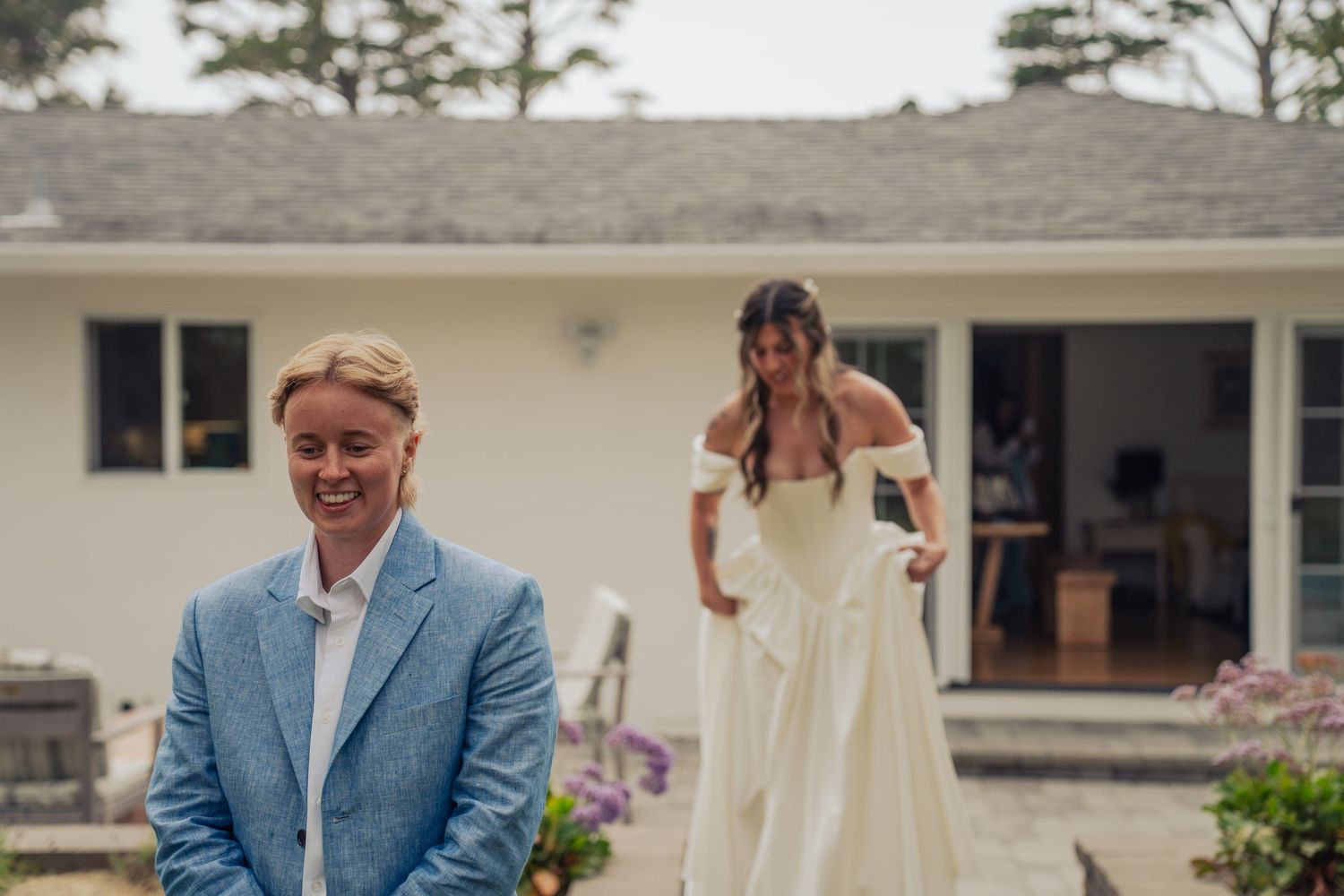 Outdoor first look wedding moment with bride in white gown approaching smiling partner. Wedding photography in Colorado and west coast.