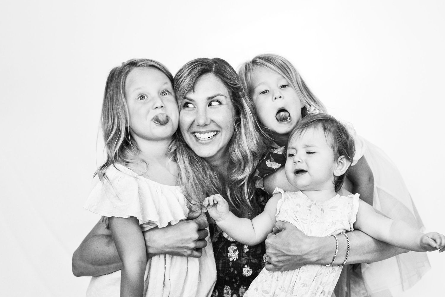 Mother and three daughters make silly faces together in a fun black and white portrait.