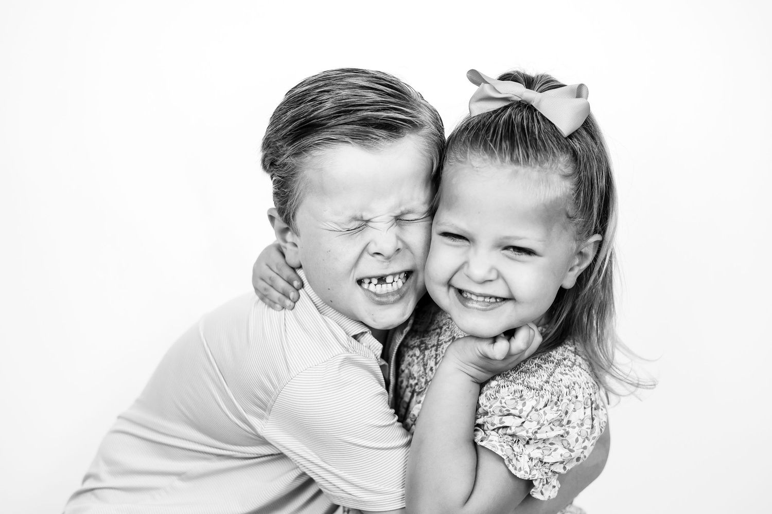 Black and white photo of two young children hugging and laughing together.