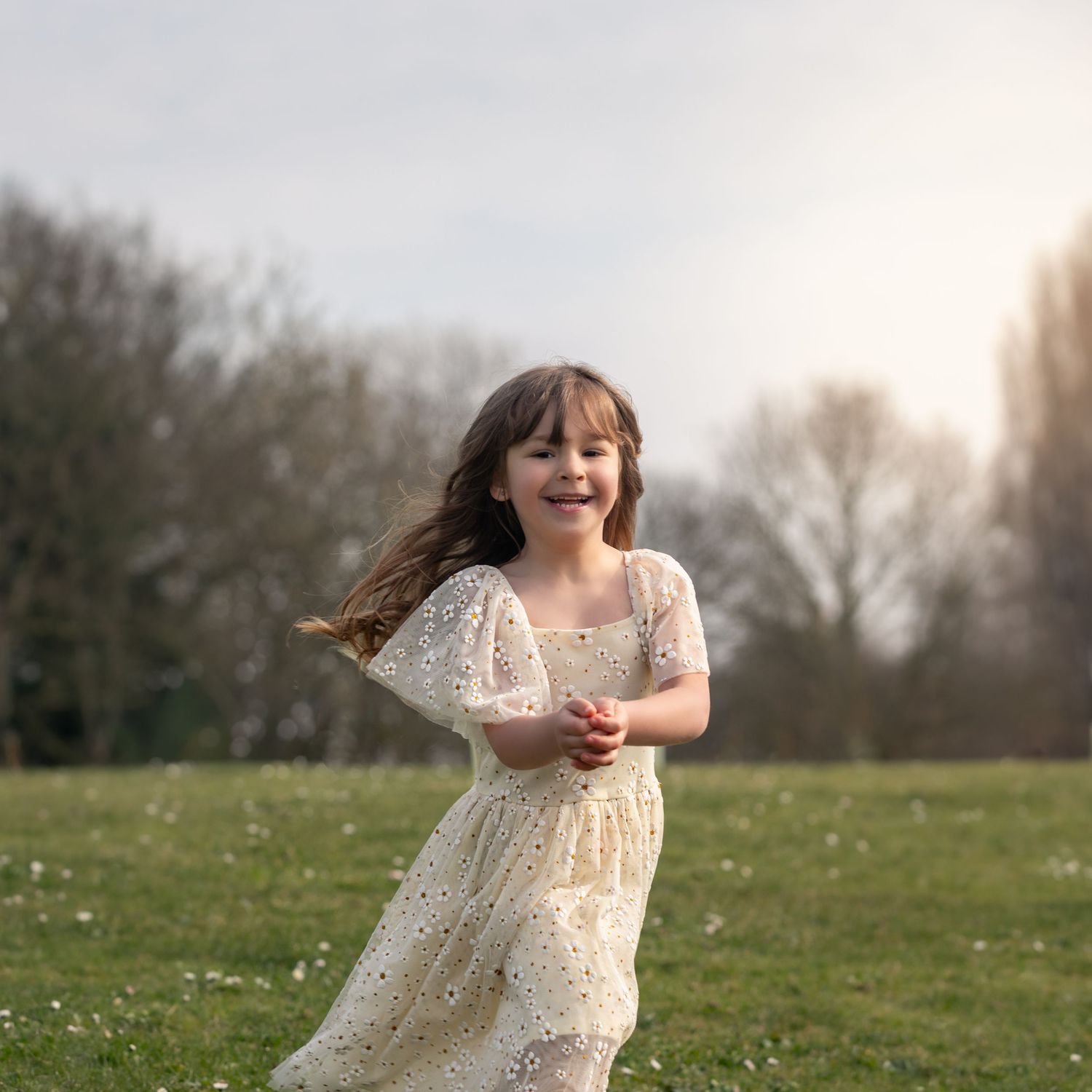 Joyful young girl in cream floral dress running through green meadow at golden sunset hour.

East Park Hull