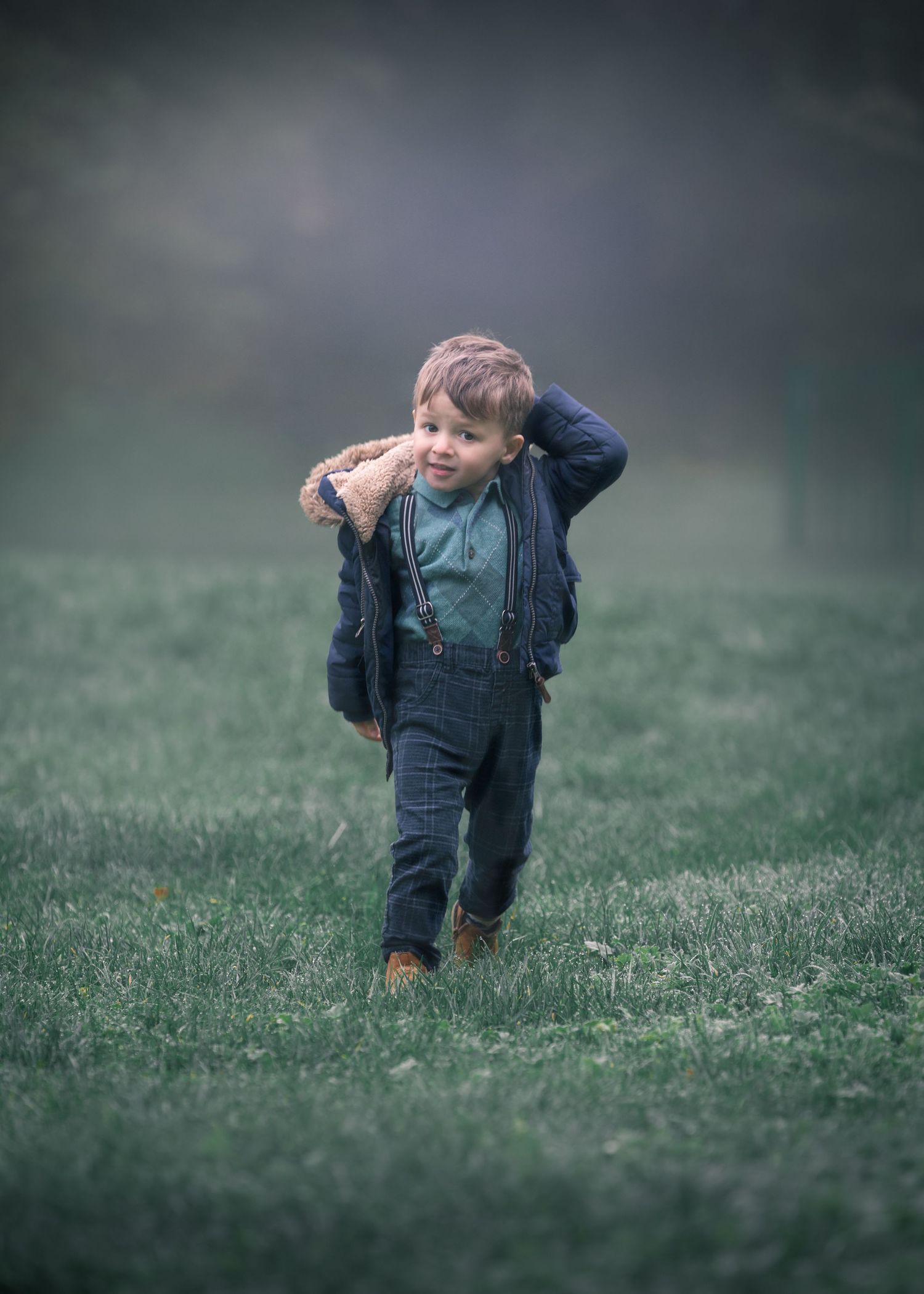 Young boy in suspenders carrying a teddy bear across a misty green meadow at dusk.

Sutton Village Hull